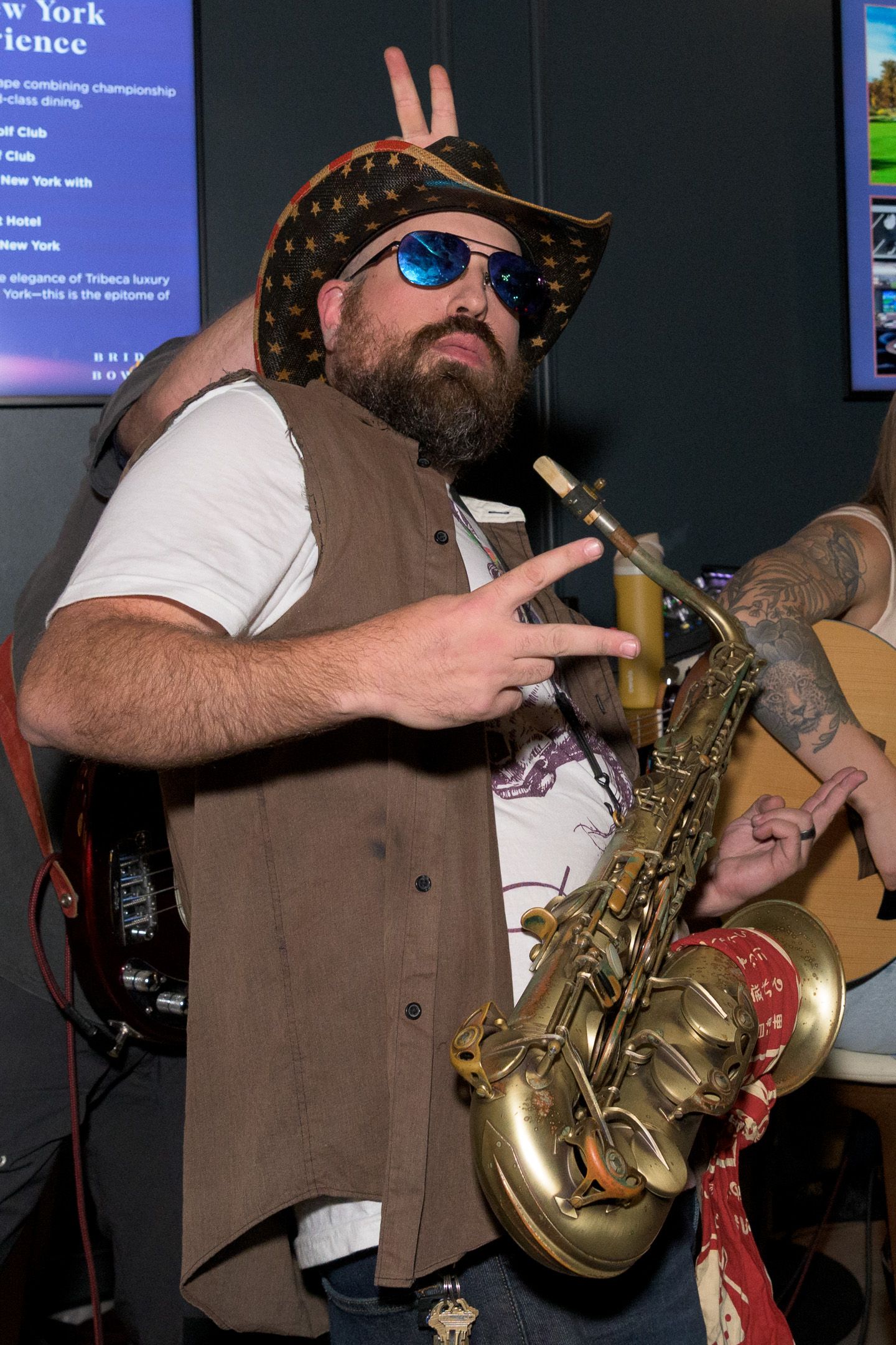 Bearded saxophonist in pirate hat performs at indoor music event.