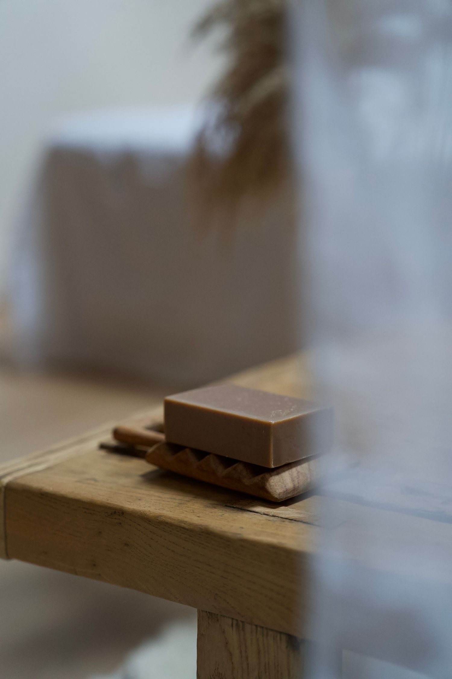 Brown soap bar sitting on wooden surface in soft focus.
