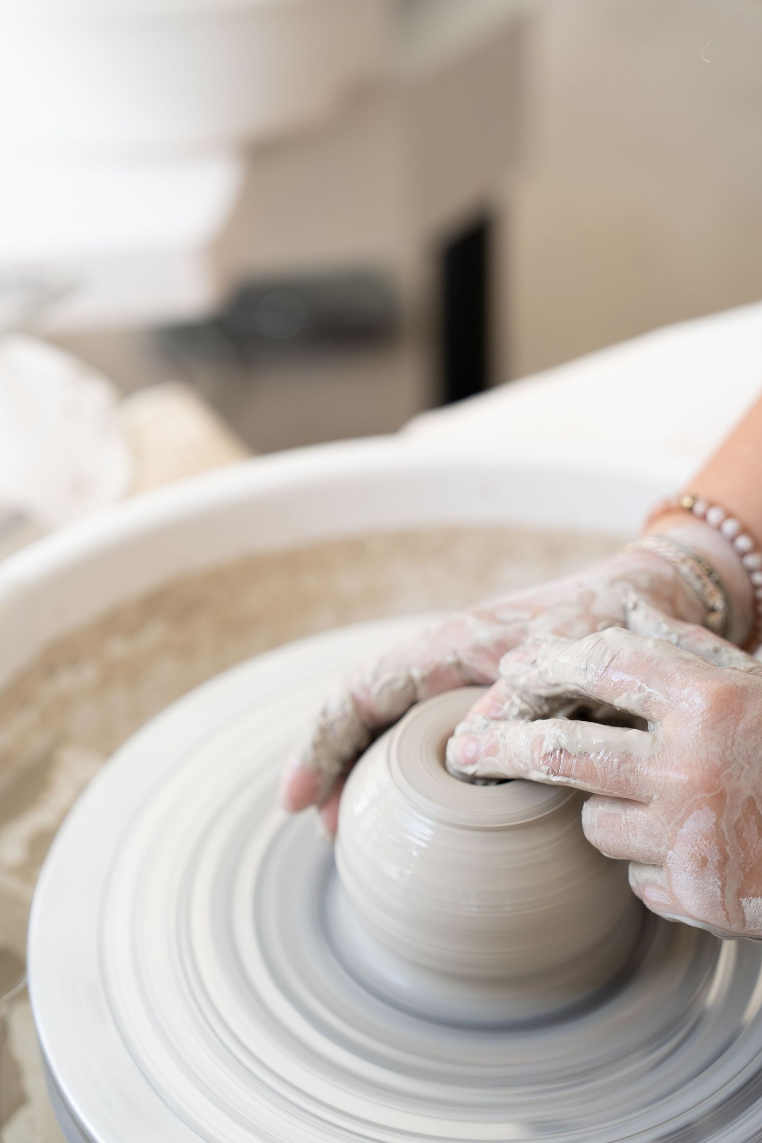 Close-up view of hands molding and smoothing clay on a spinning wheel.