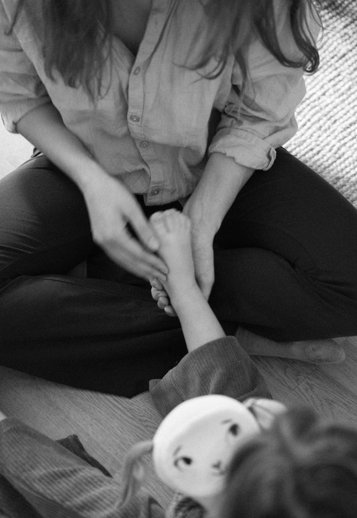 Black and white close-up photo of a person's hands gently petting a resting dog.