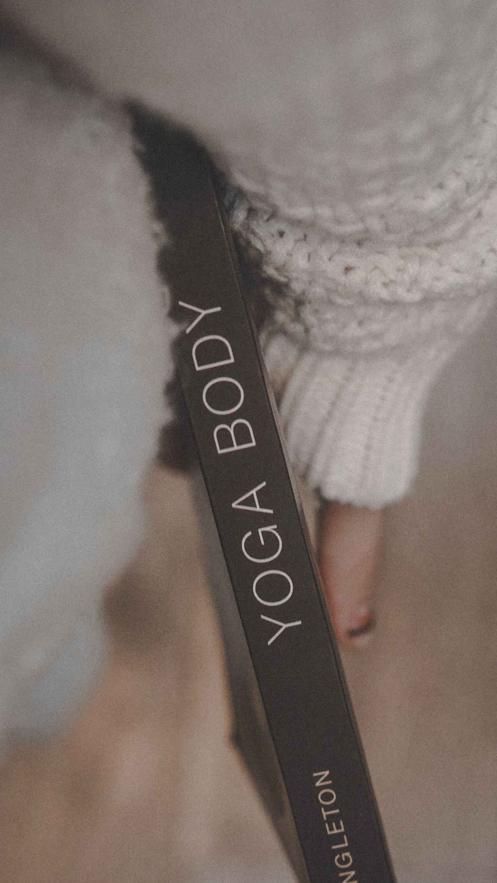 Black yoga body text visible on book spine against knitted fabric.