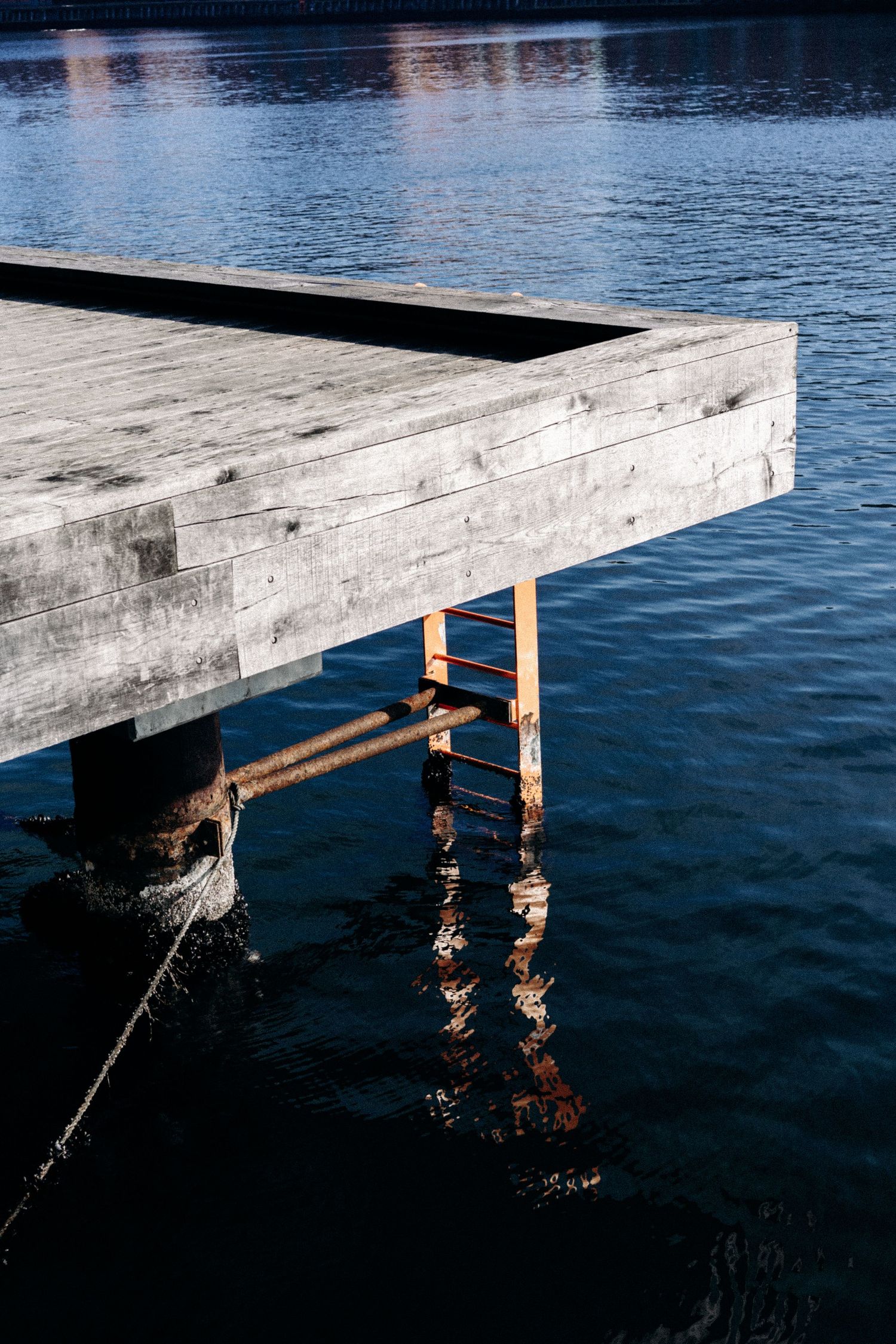 Weathered wooden dock platform extending over calm blue water.