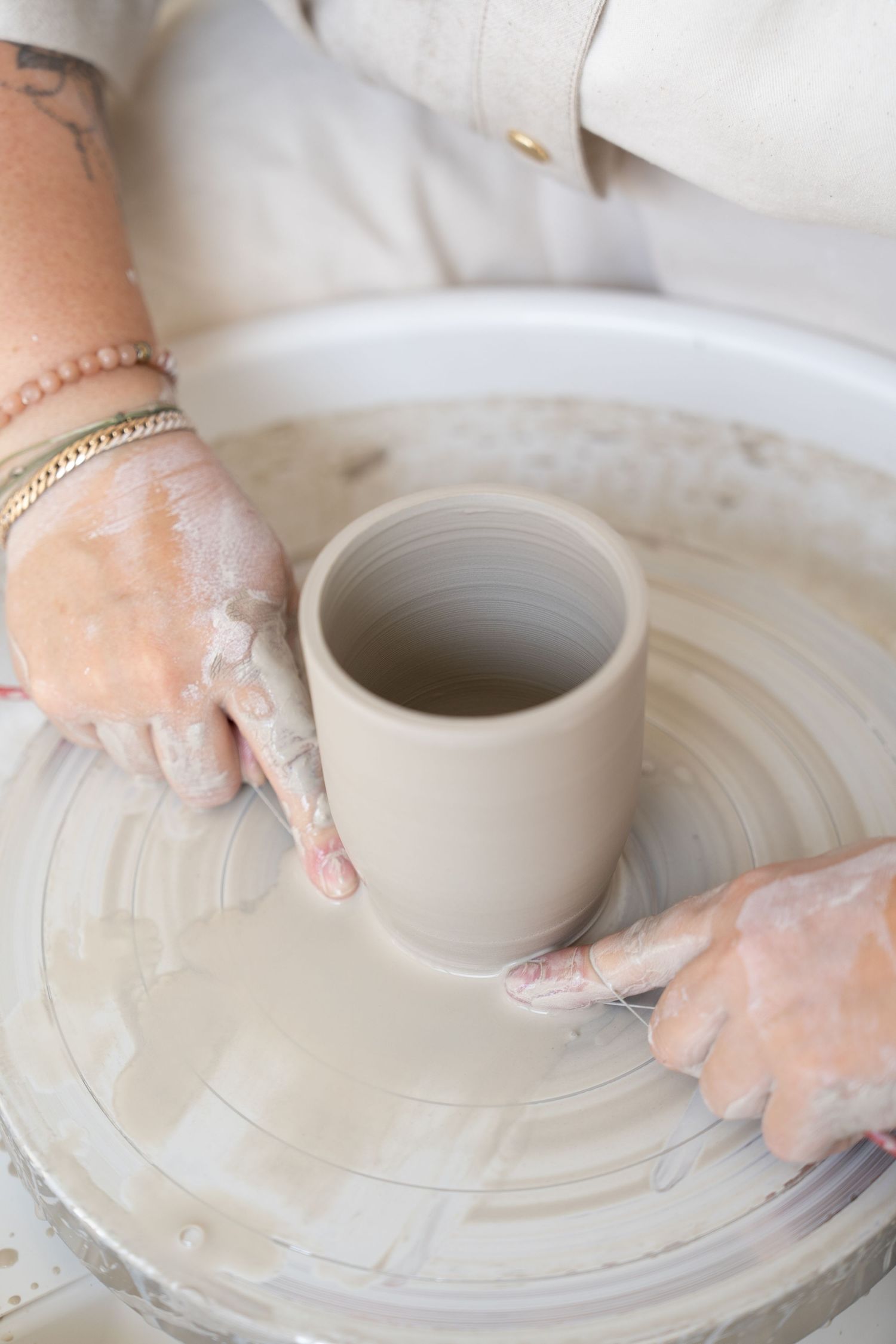 Clay vessel being shaped on a pottery wheel with skilled hand movements.