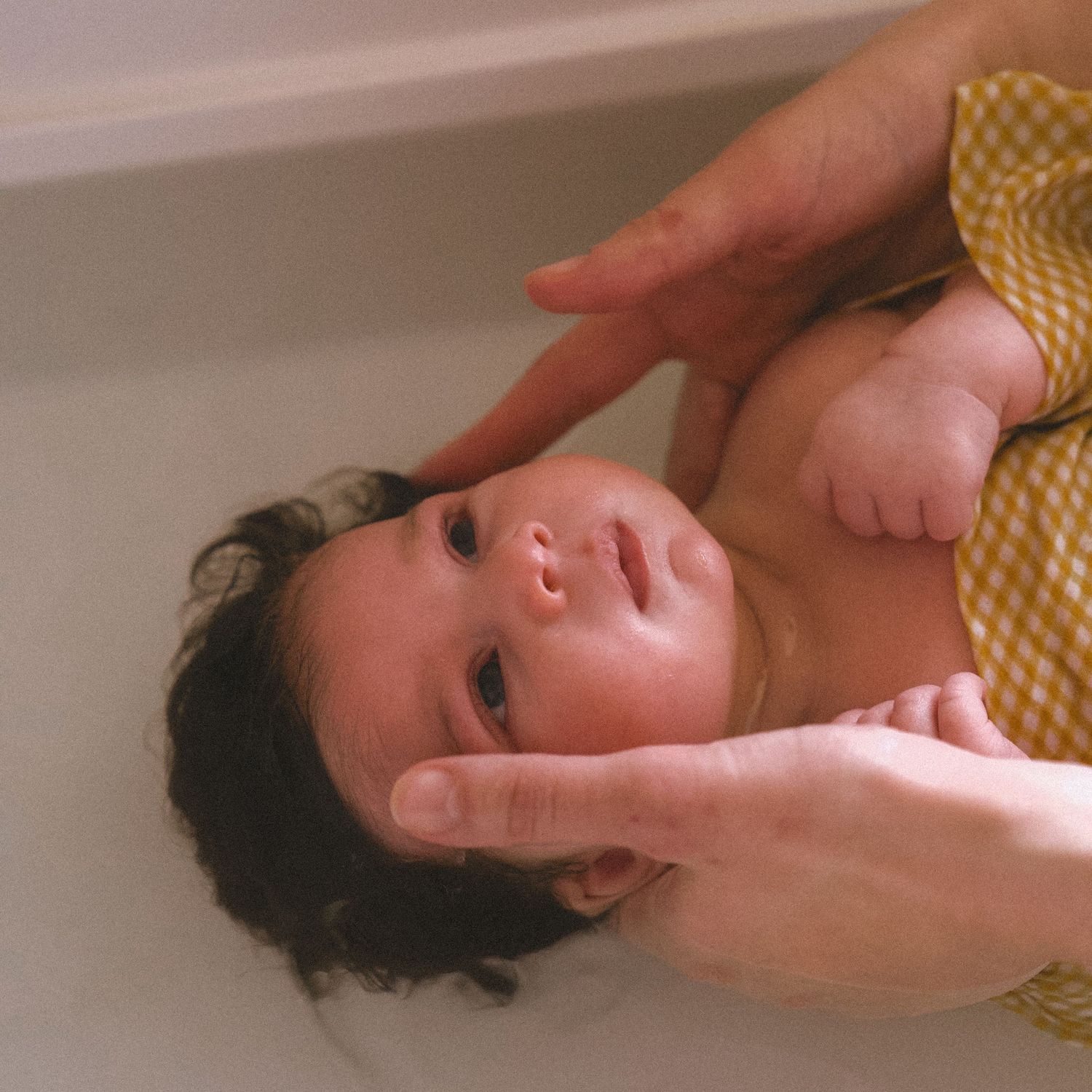 A baby lying in a bathtub filled with warm water during bath time.