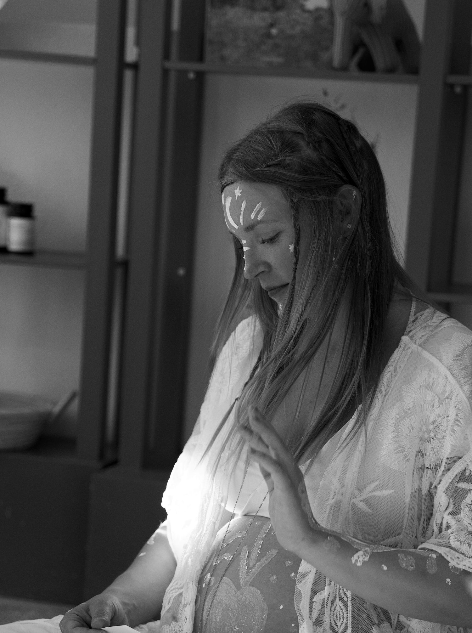 Person in white clothing working at a desk in black and white photography.