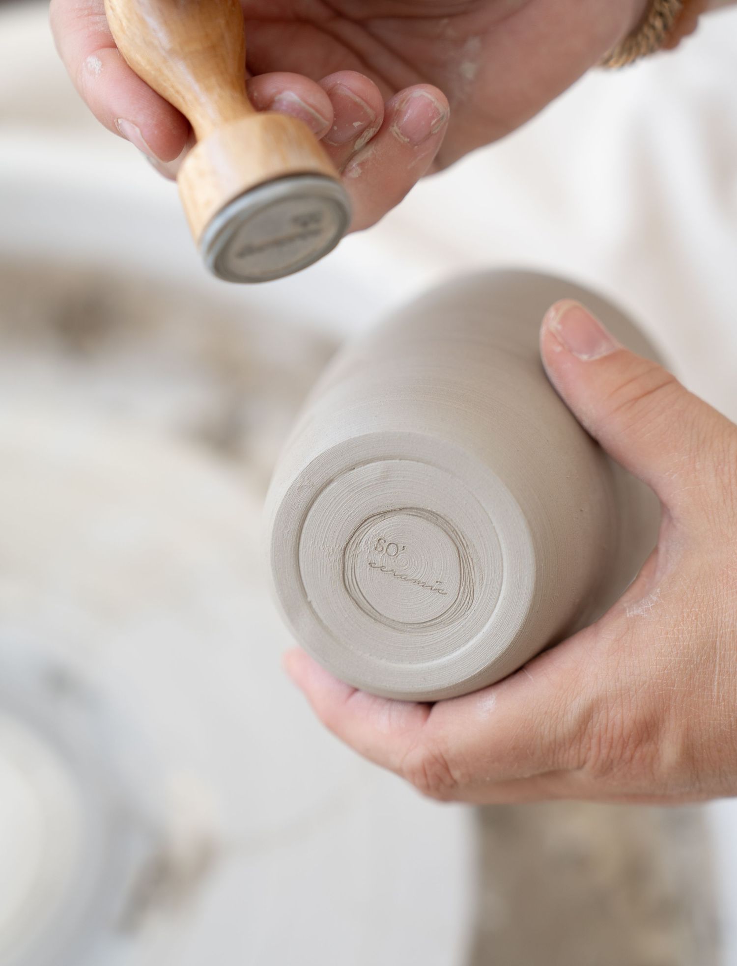 Close-up of hands working with clay pottery on a wheel, showing detailed shaping techniques.