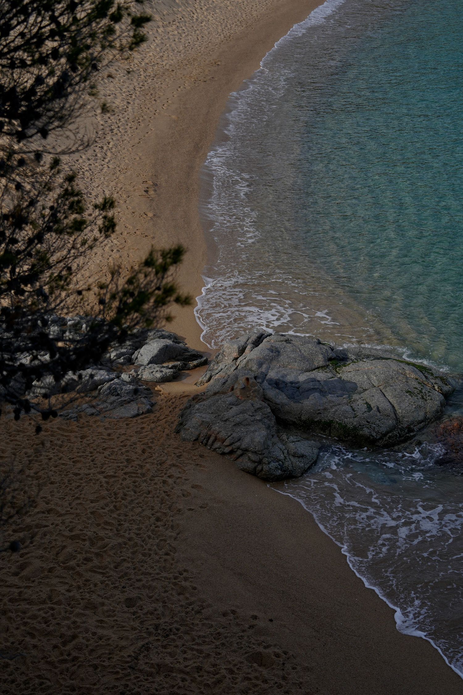 Secluded sandy beach cove with turquoise waters and gentle waves lapping at the shore.