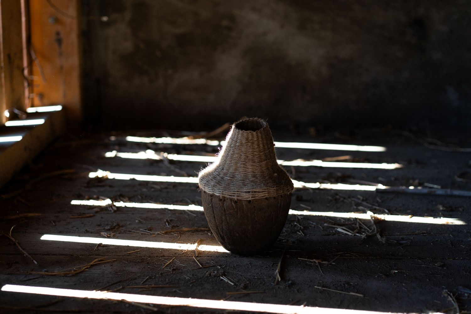 Dramatic shadows cast by sunlight streaming through windows onto a dark wooden floor in an empty room.