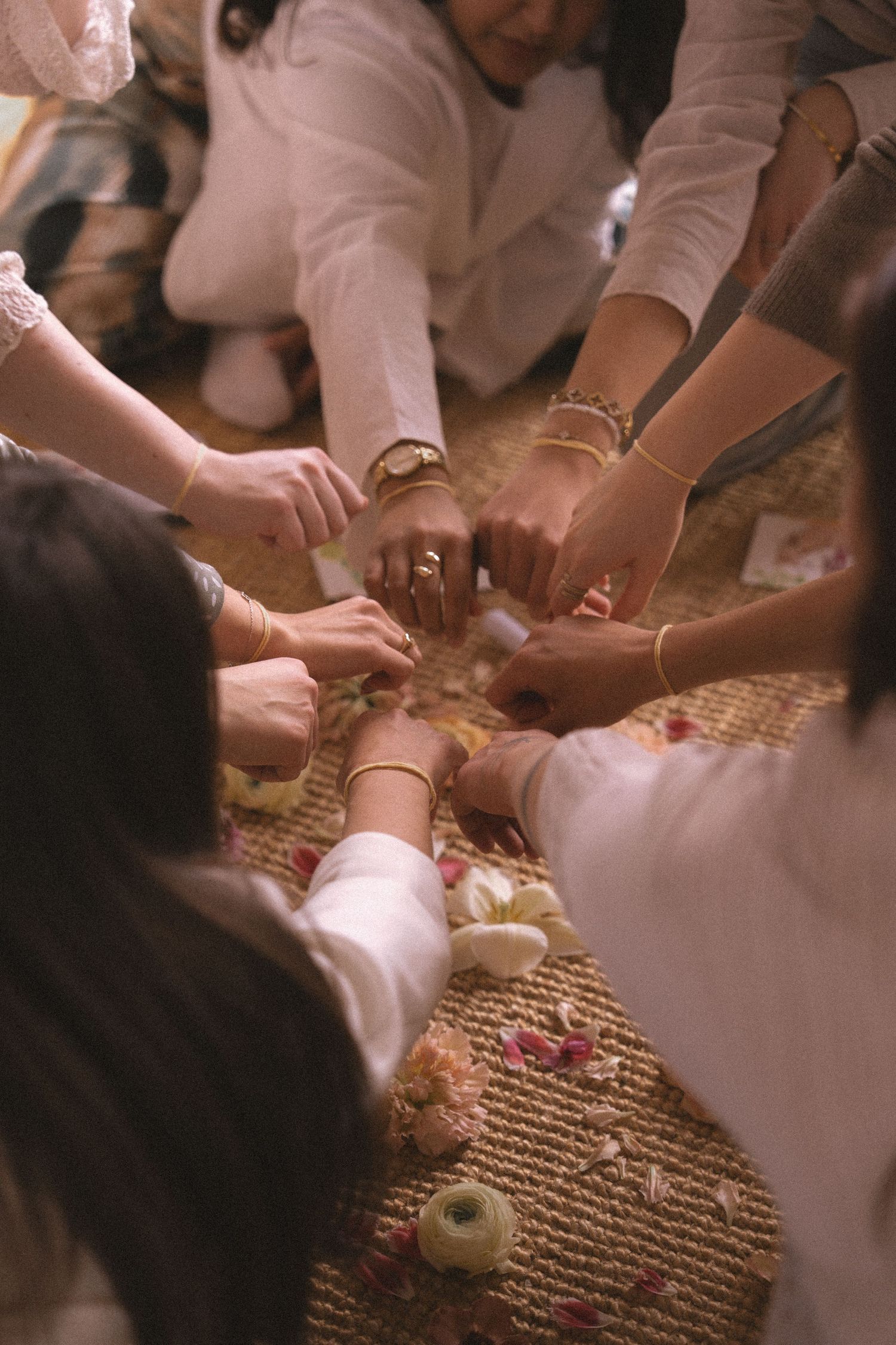 Multiple hands reach for a traditional Chinese tea ceremony set arranged on a woven mat during a cultural gathering.