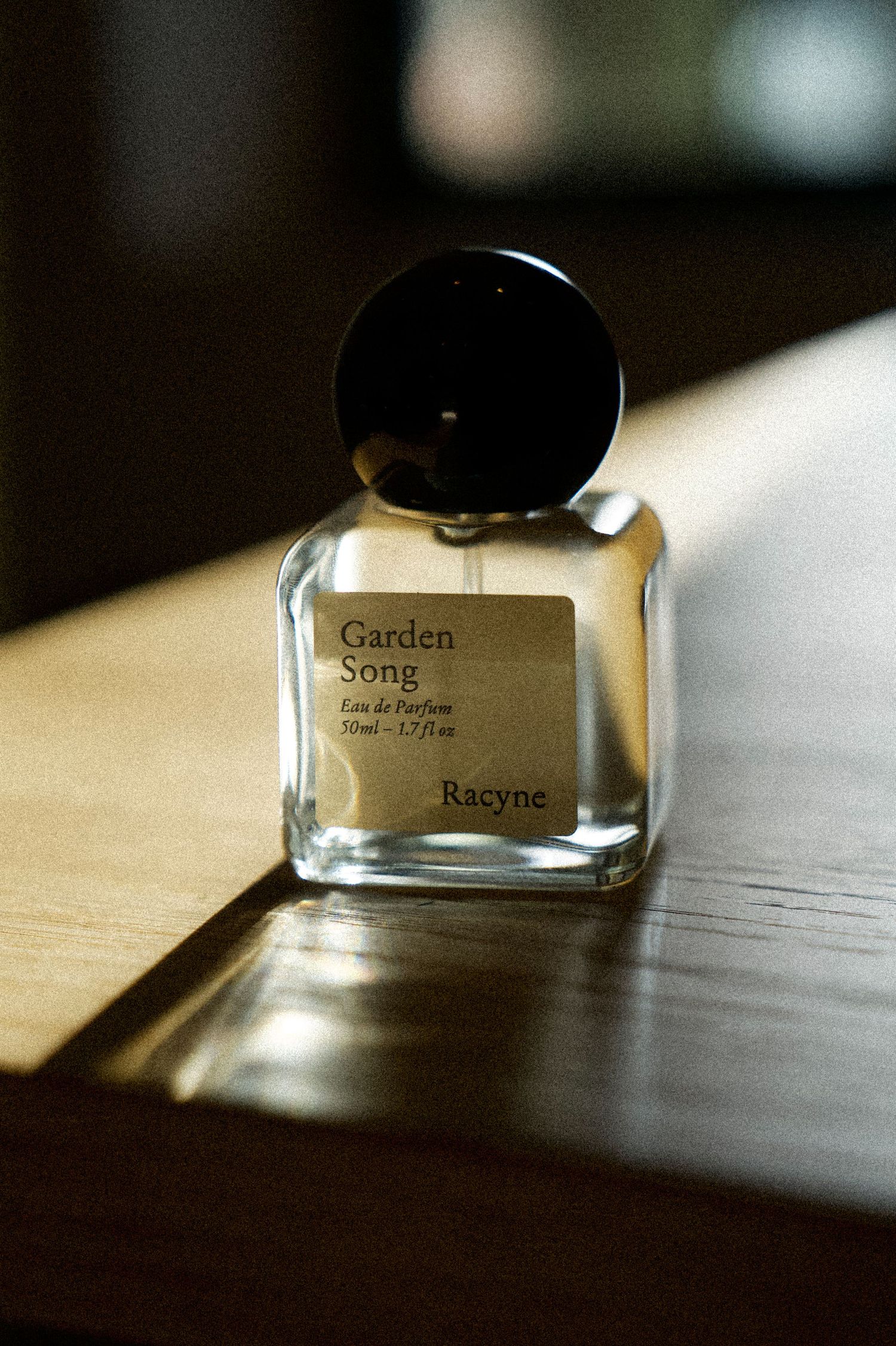 A perfume bottle with different labels shown in a minimalist style against a light wooden surface.
