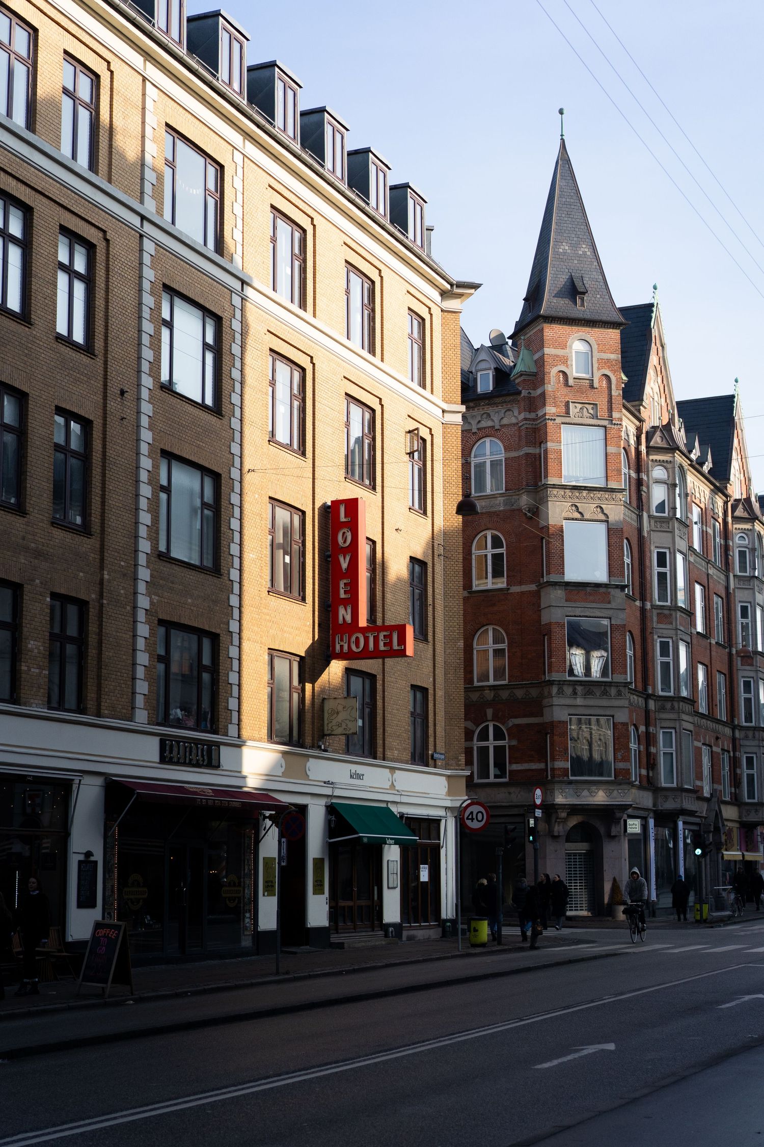 Historic European street with mix of modern and Victorian architecture in late afternoon light.