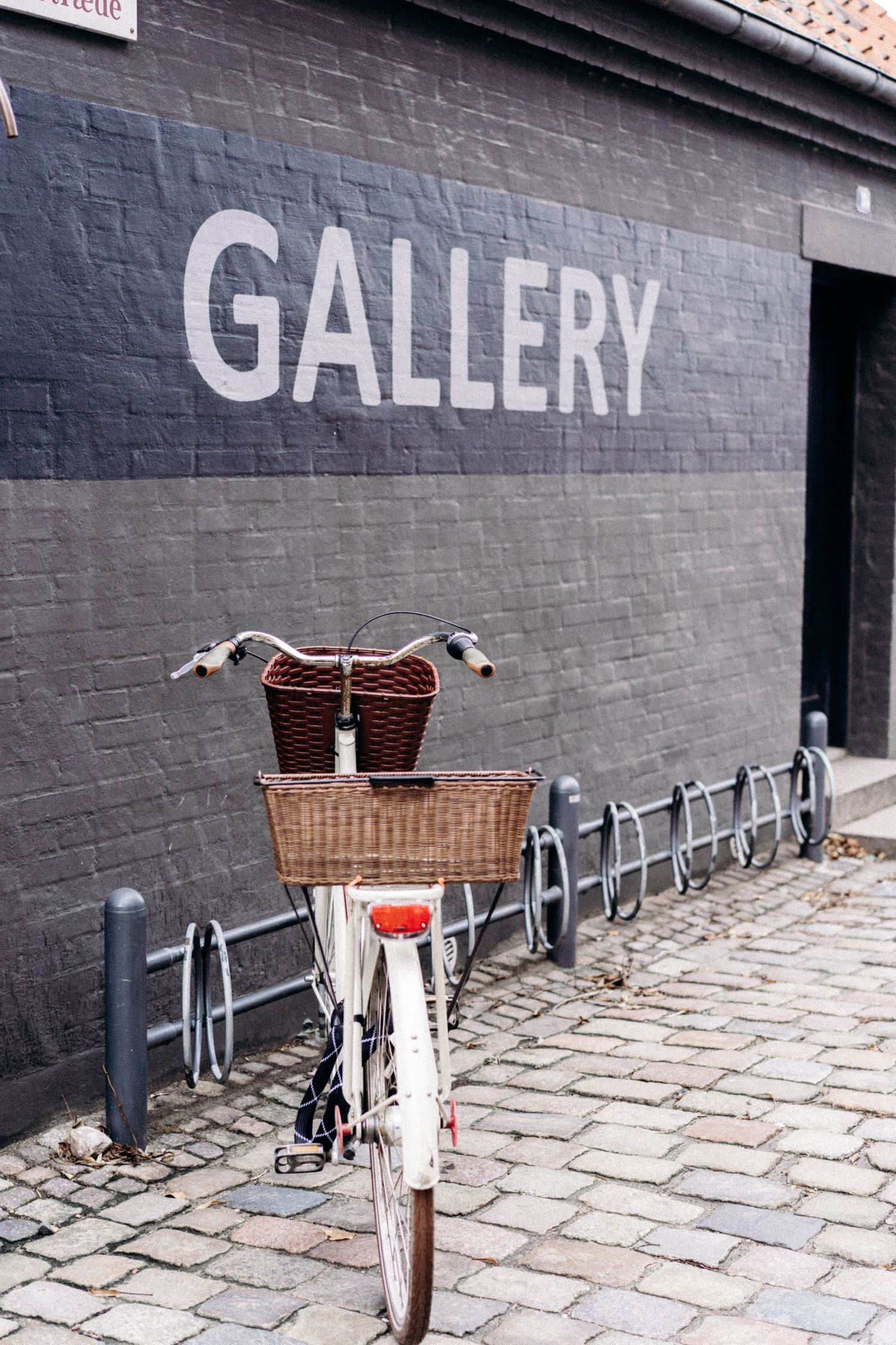Bicycles parked along a grey wall with 'GALLERY' text painted on it.