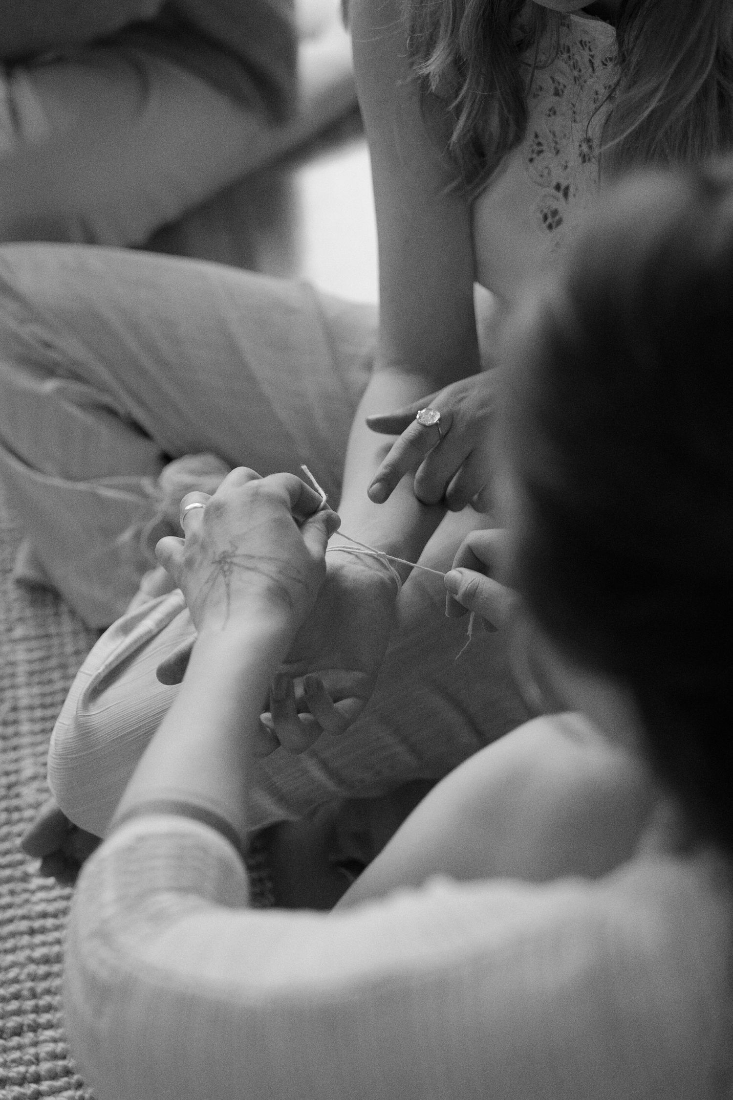 Black and white photograph showing gentle hands providing care and comfort to someone resting on a bed.