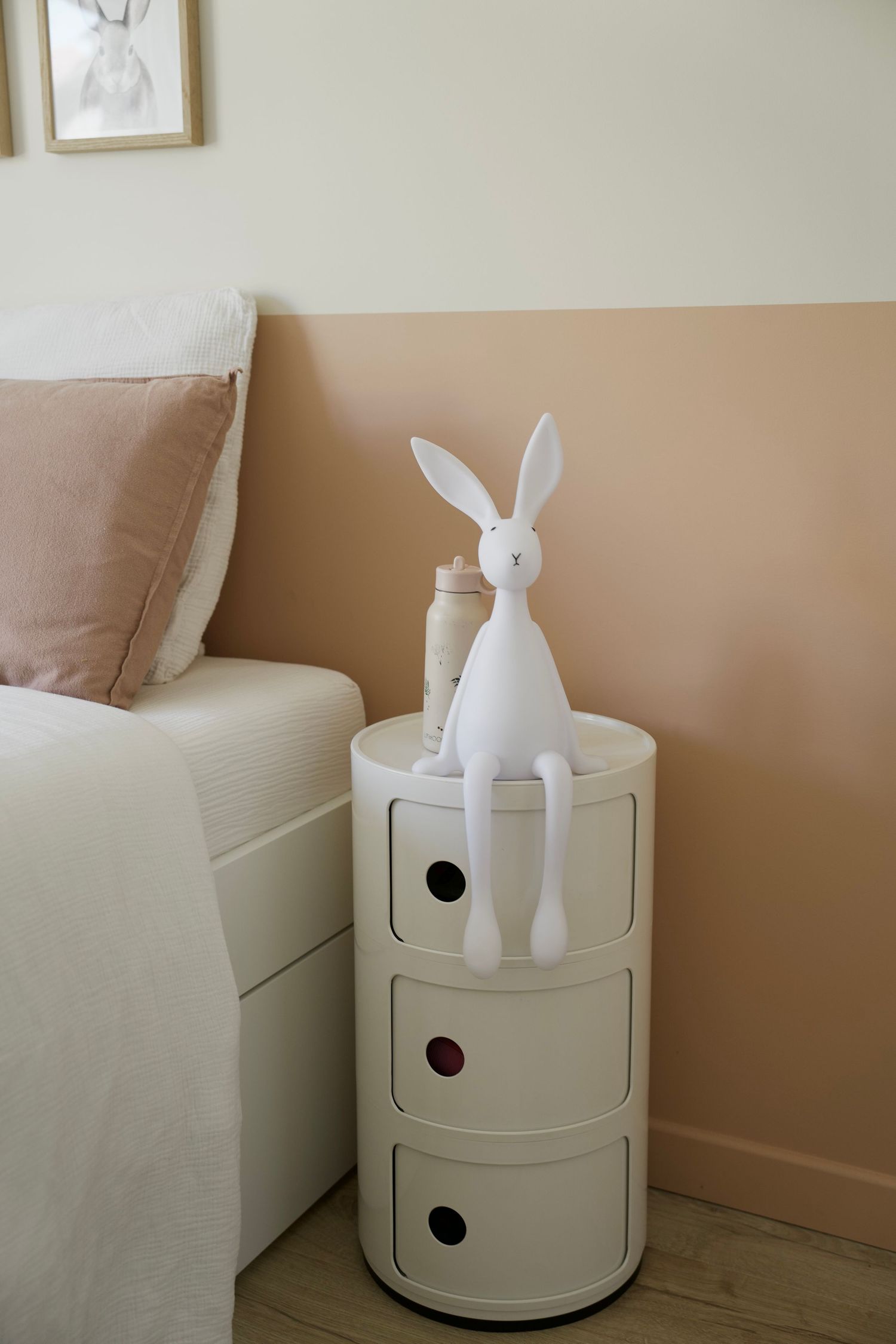 Modern white storage unit with decorative bunny figure on top next to a sofa.