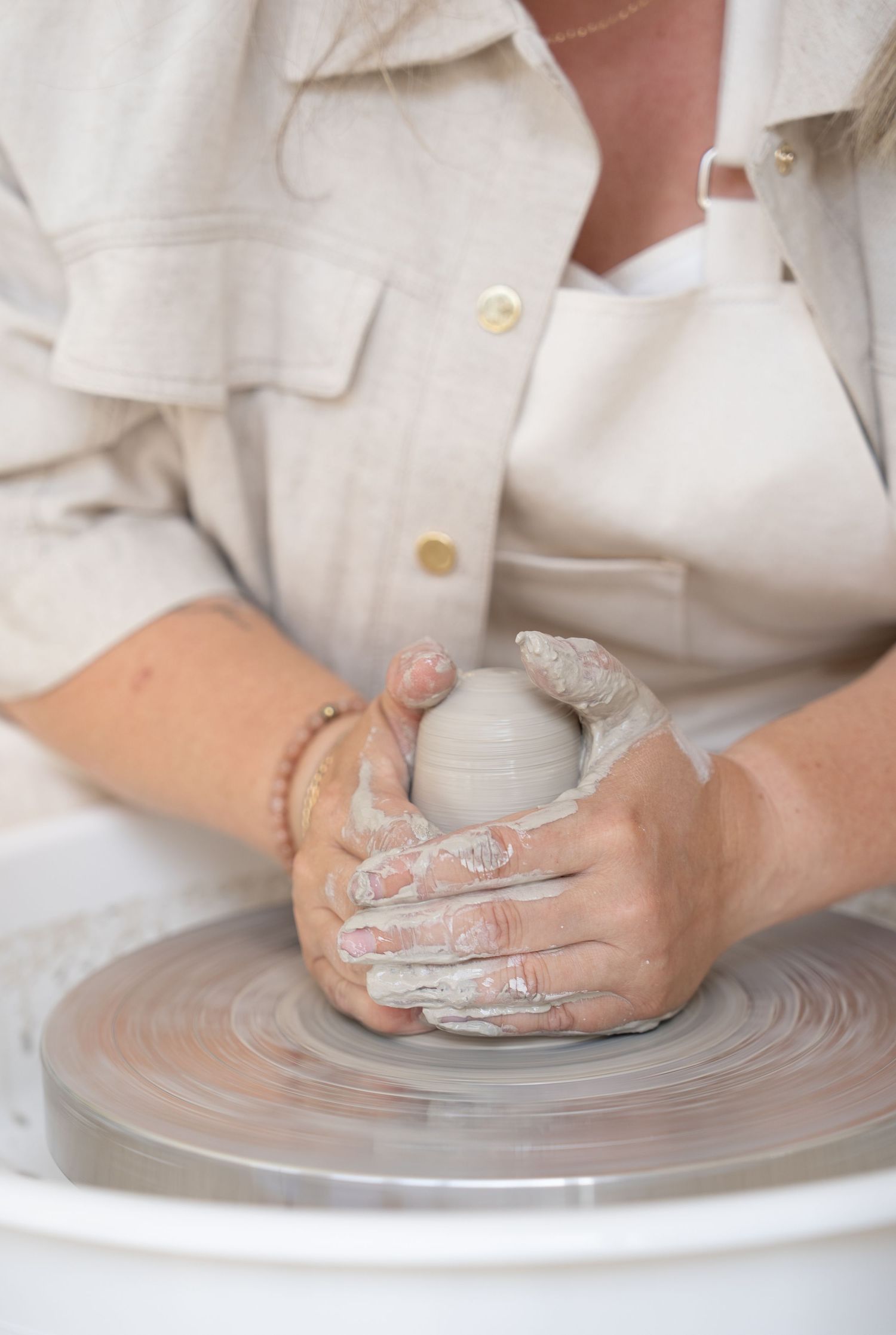 Detailed view of hands carefully shaping clay on pottery wheel.
