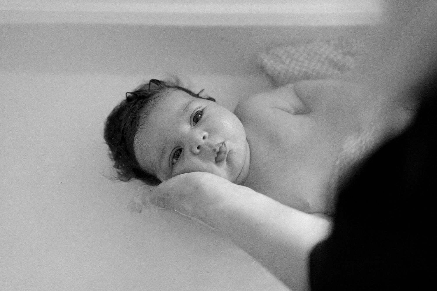 A young child rests peacefully on a pillow in this intimate black and white photograph.