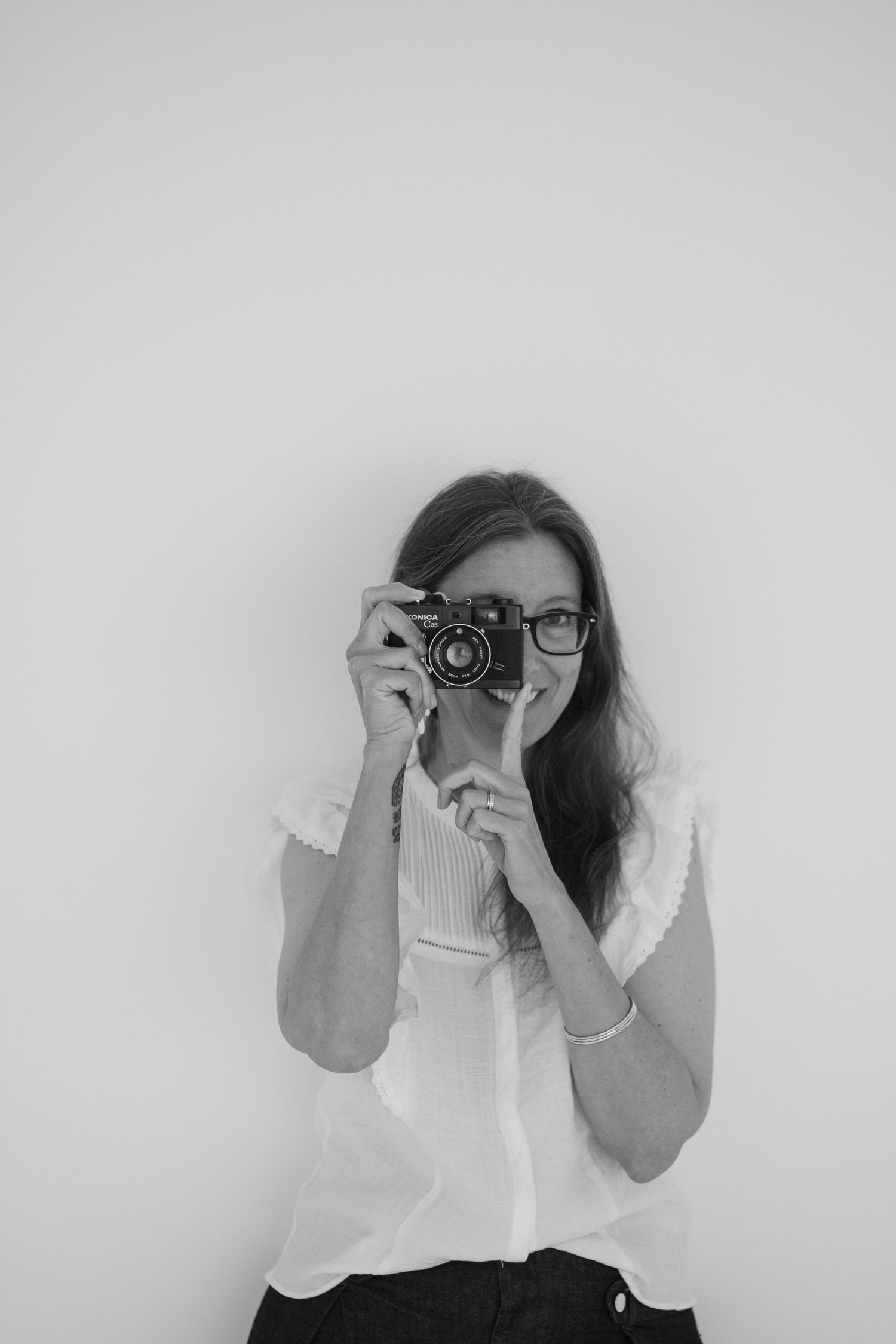 A series of four black and white photos showing someone taking pictures with a vintage camera against a white background.