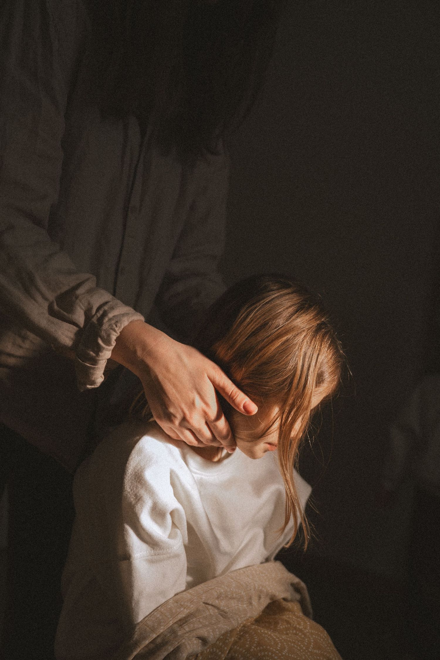 A series of dark moody photographs showing someone in a white shirt against a shadowy background.