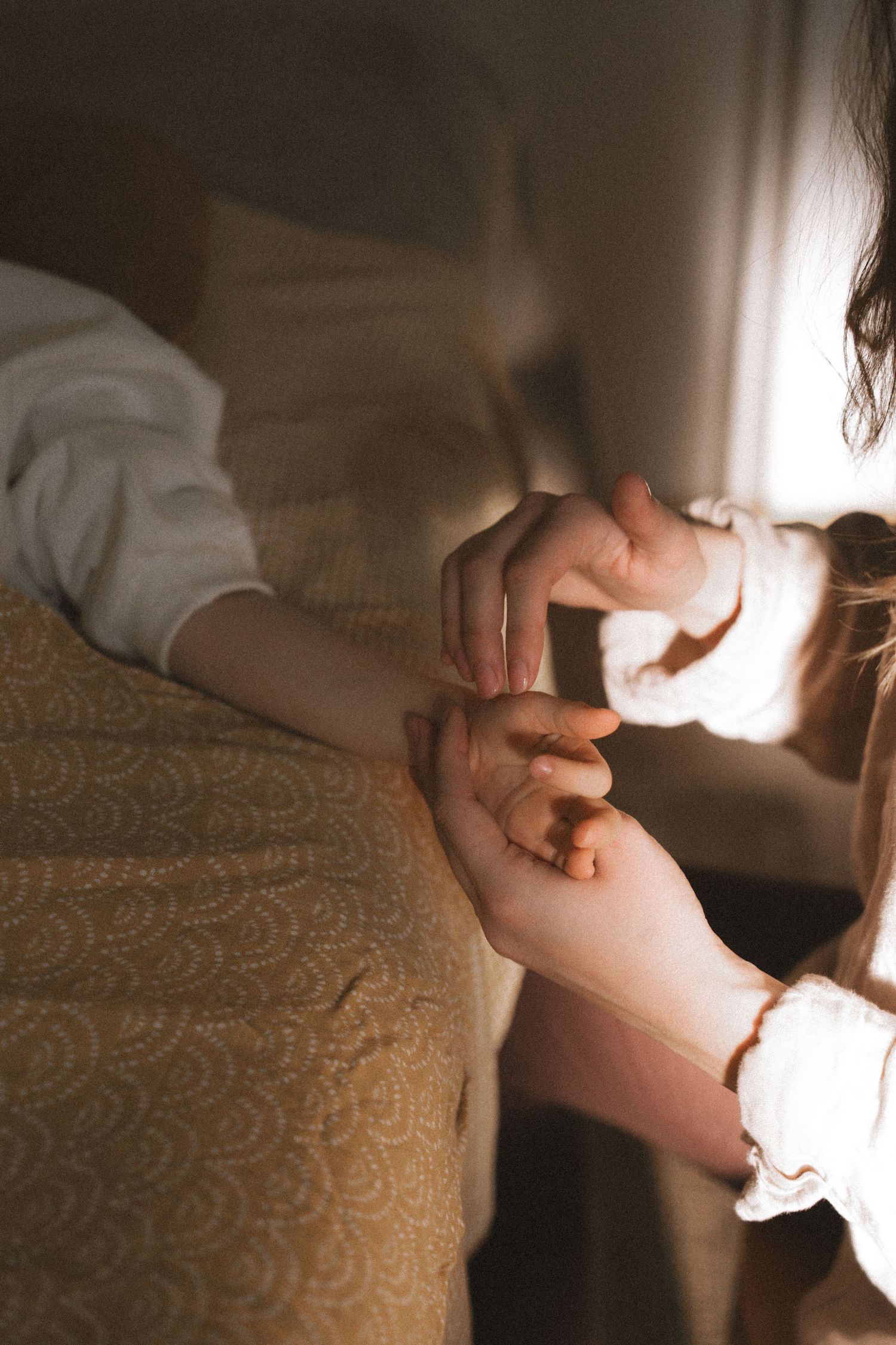 A series of moody photographs showing hands gently holding and caressing against a textured beige fabric background.