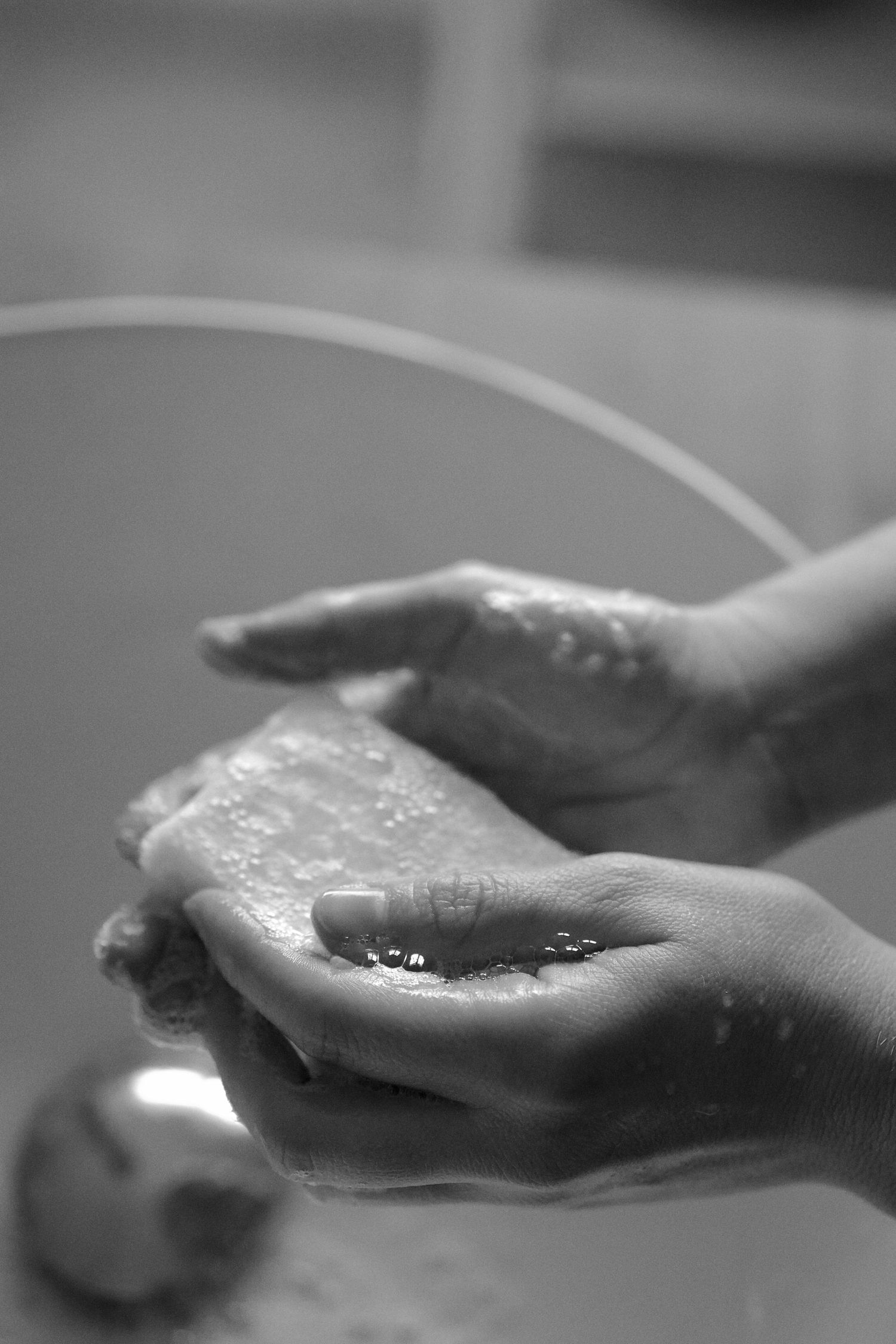 Hands cupped together holding clear liquid with dramatic lighting.