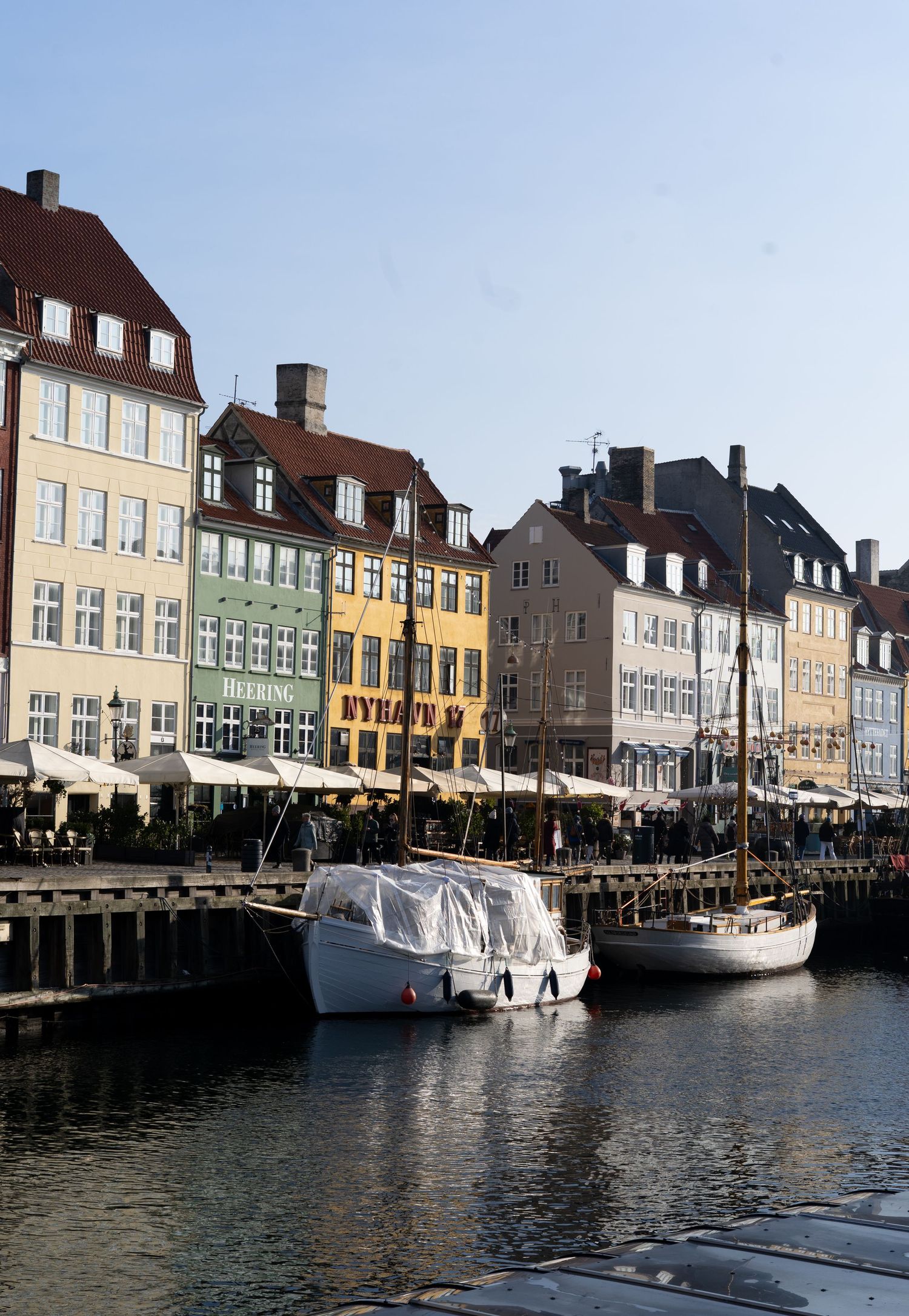 Colorful historic buildings along Nyhavn canal waterfront in Copenhagen with boats docked.