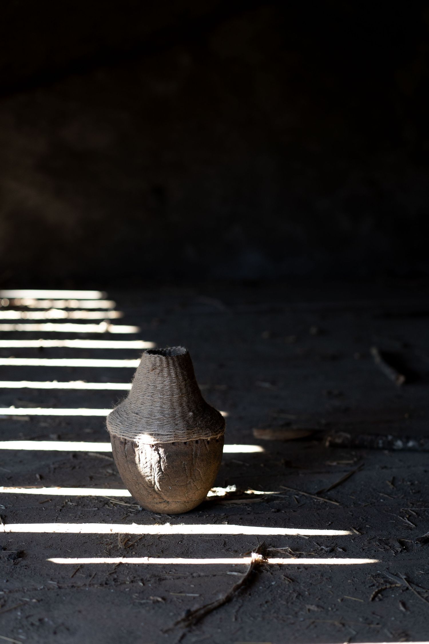 Dramatic lighting creates striped shadows across a dark floor with a spherical object.