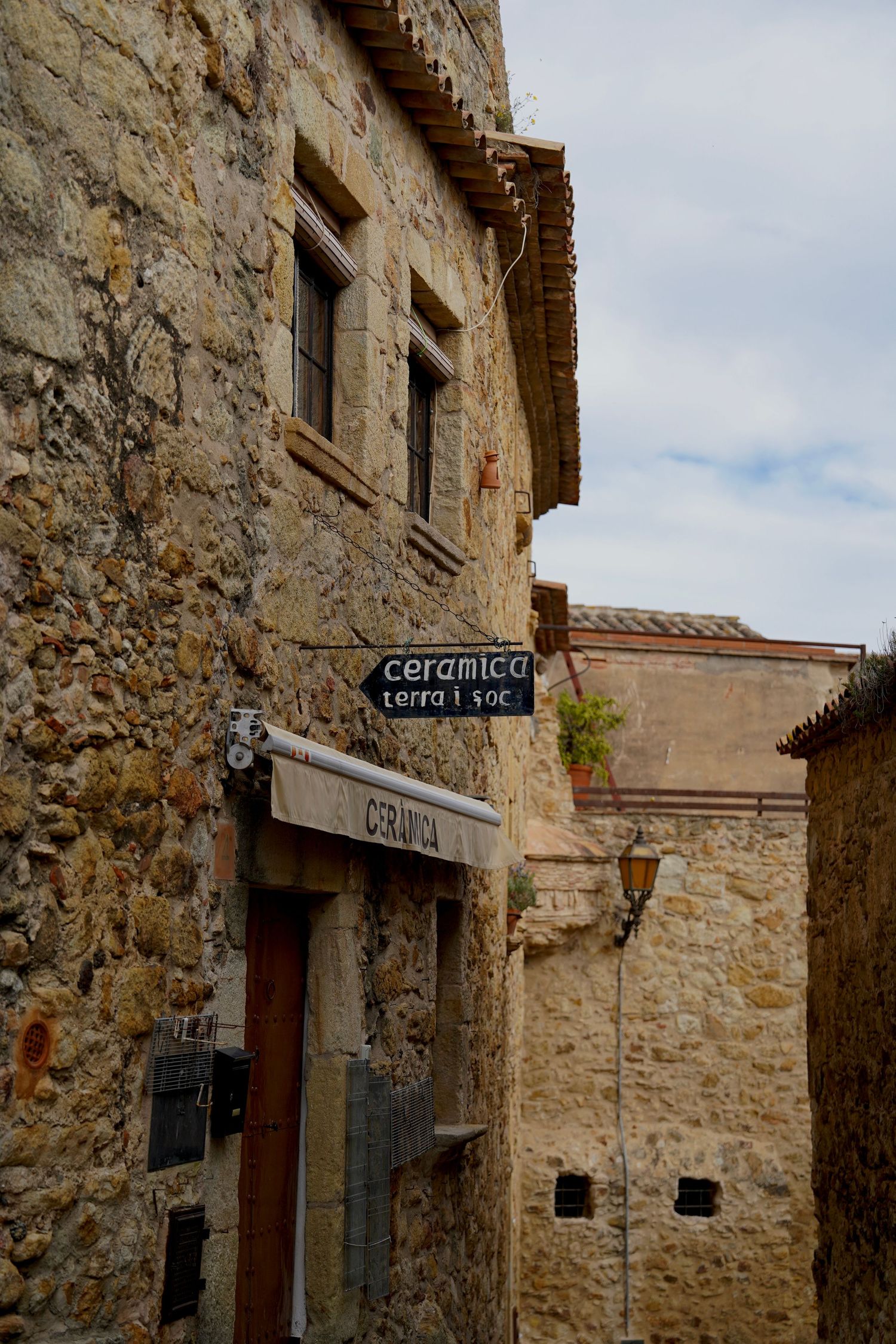 Rustic stone buildings with traditional architecture line a charming Mediterranean village street.