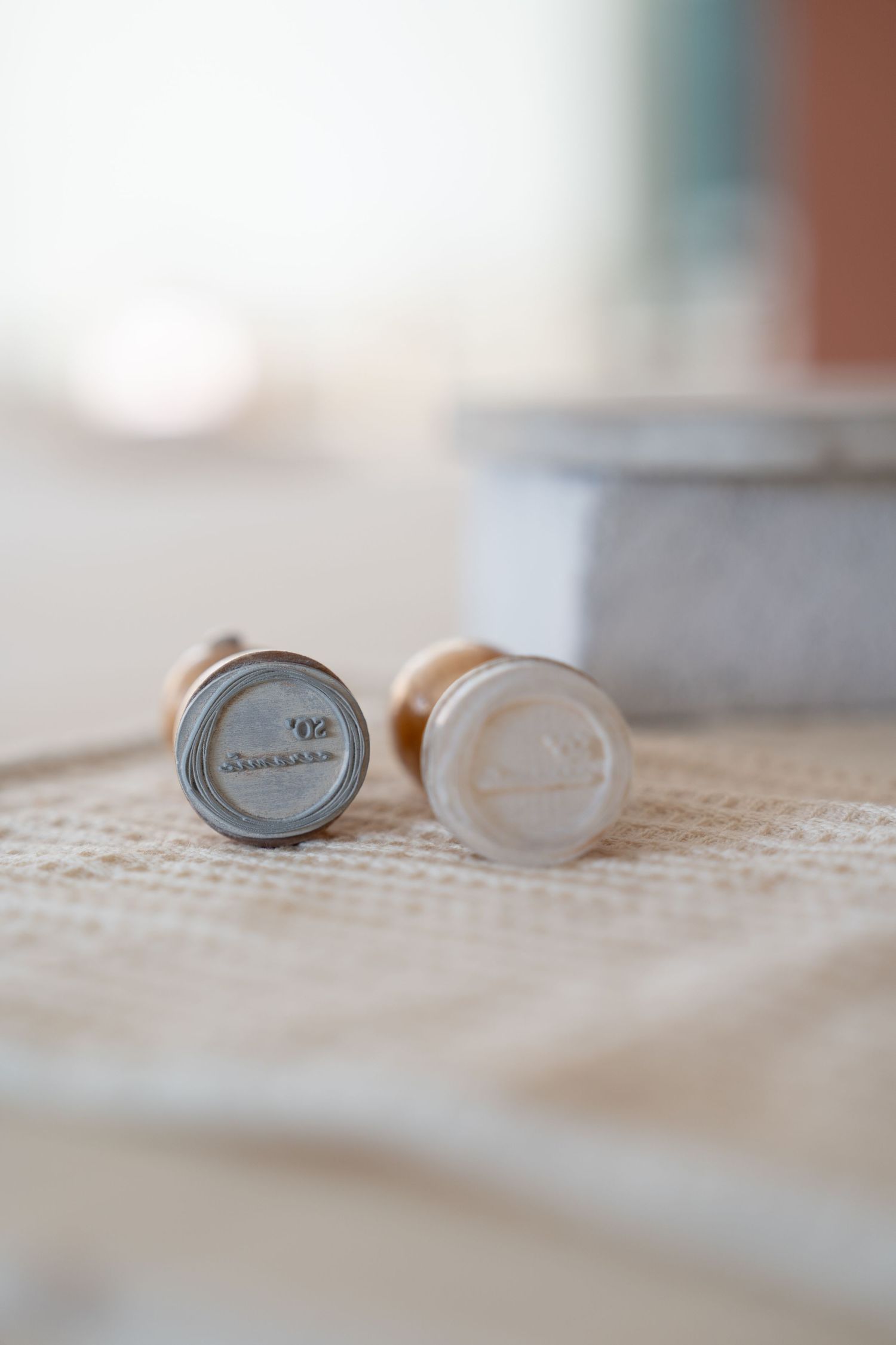 Small ceramic lids arranged on a textured fabric surface.