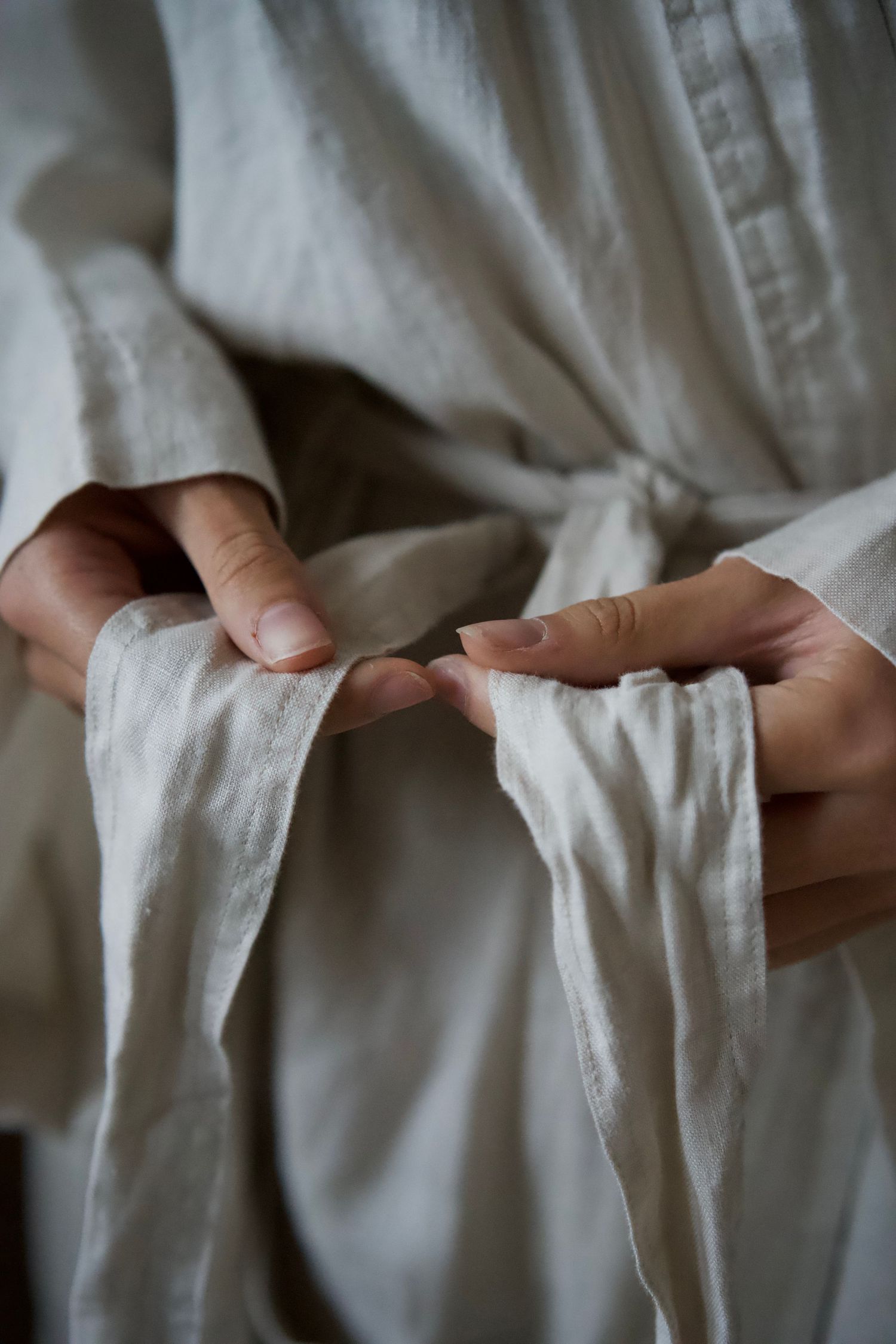 Close-up of hands adjusting white fabric pleats or folds.