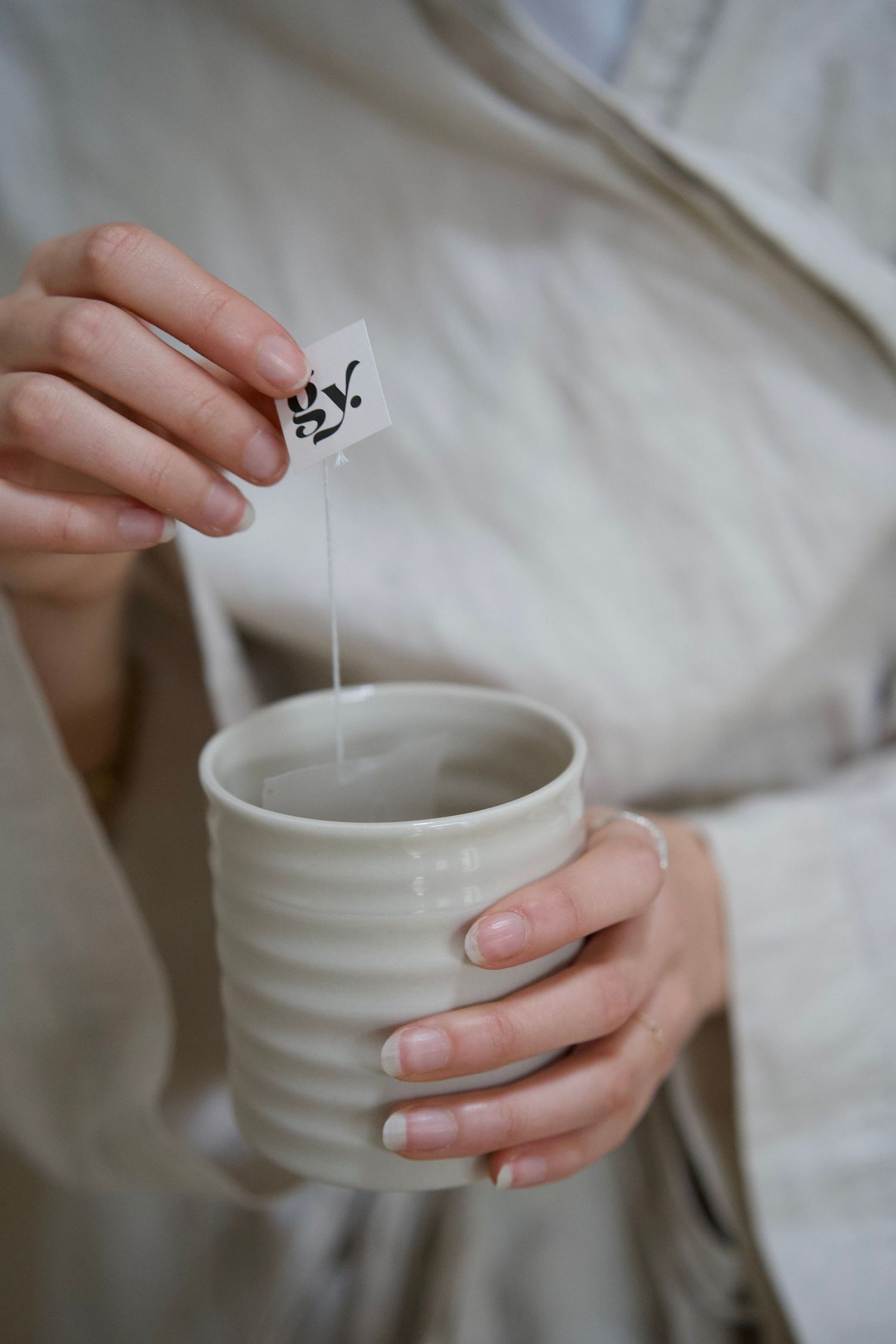 Preparing tea with a tea bag in a white ribbed ceramic mug.