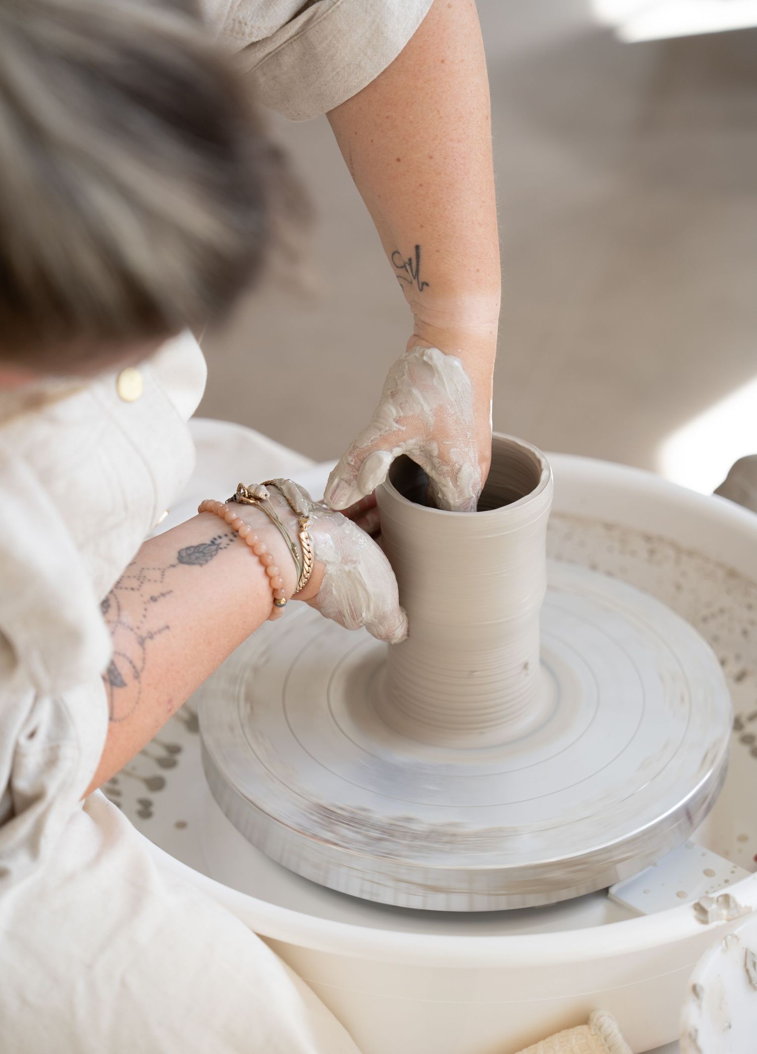 Close-up of hands shaping clay on a pottery wheel with precise movements.