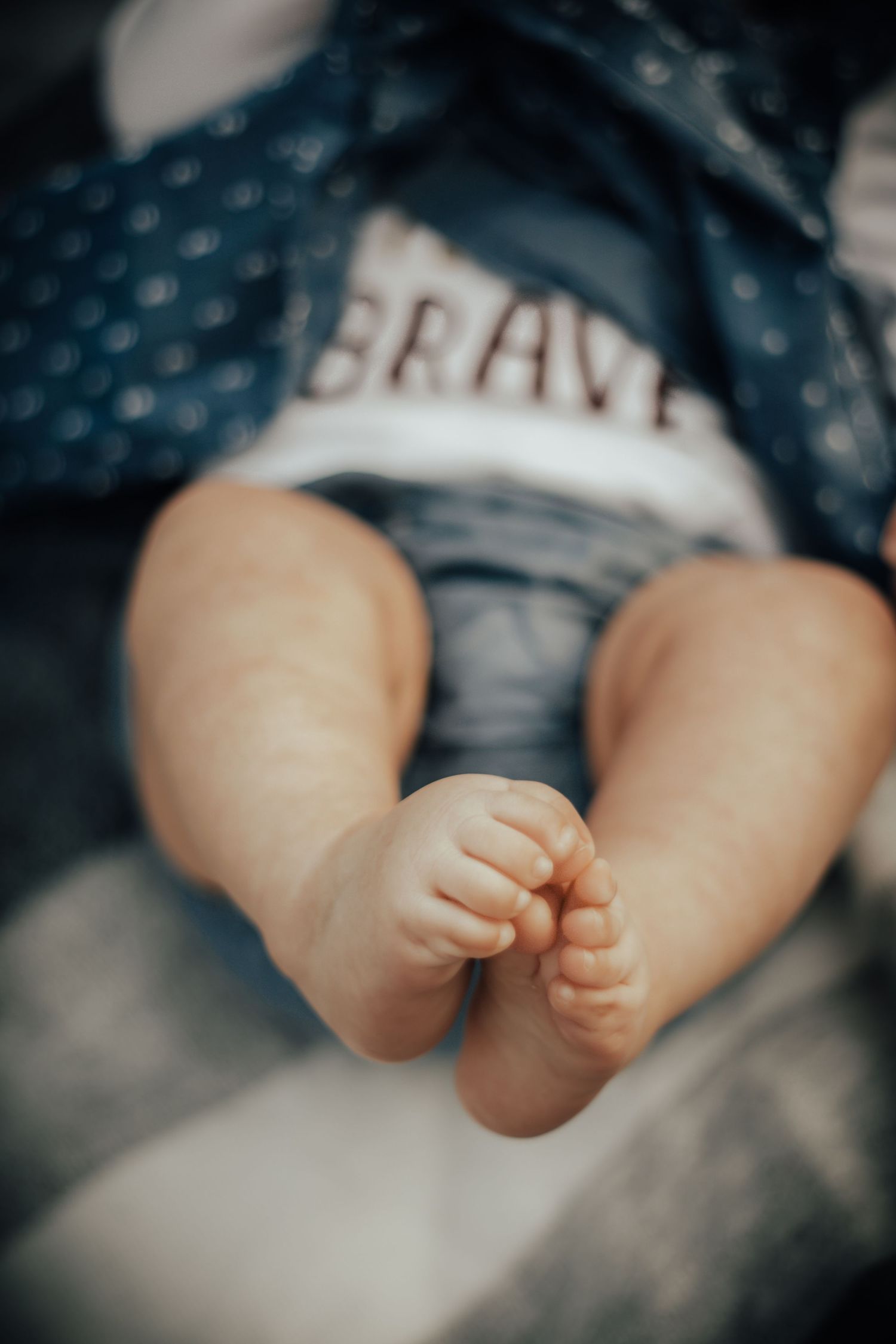 Newborn baby wrapped in a cozy blanket during lifestyle session in Bentonville Arkansas with parents looking down