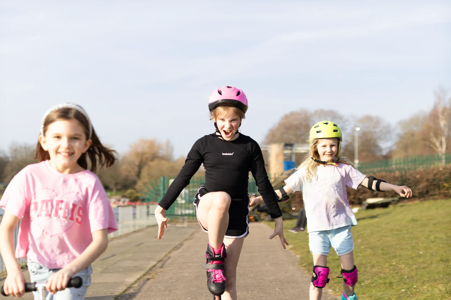Three children rollerblading together on path during sunny day.