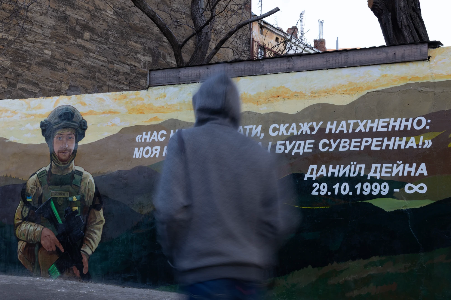 Person viewing street art mural with military figure and Ukrainian text.