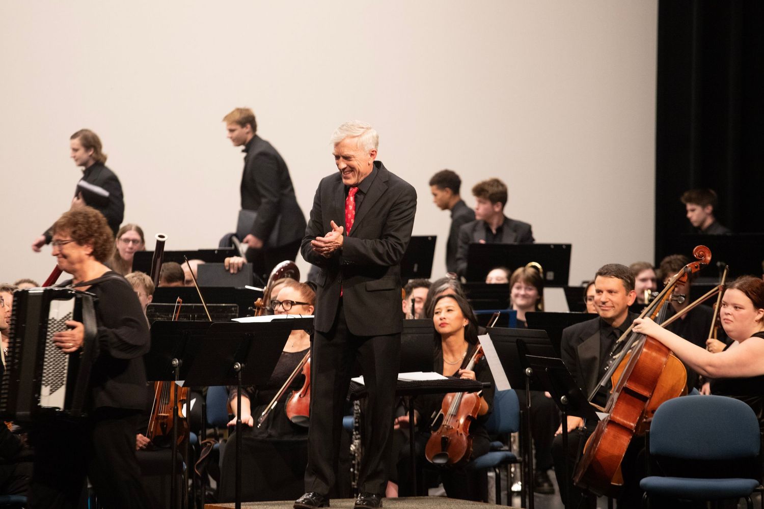 Orchestra performers and conductor on stage during classical music performance.