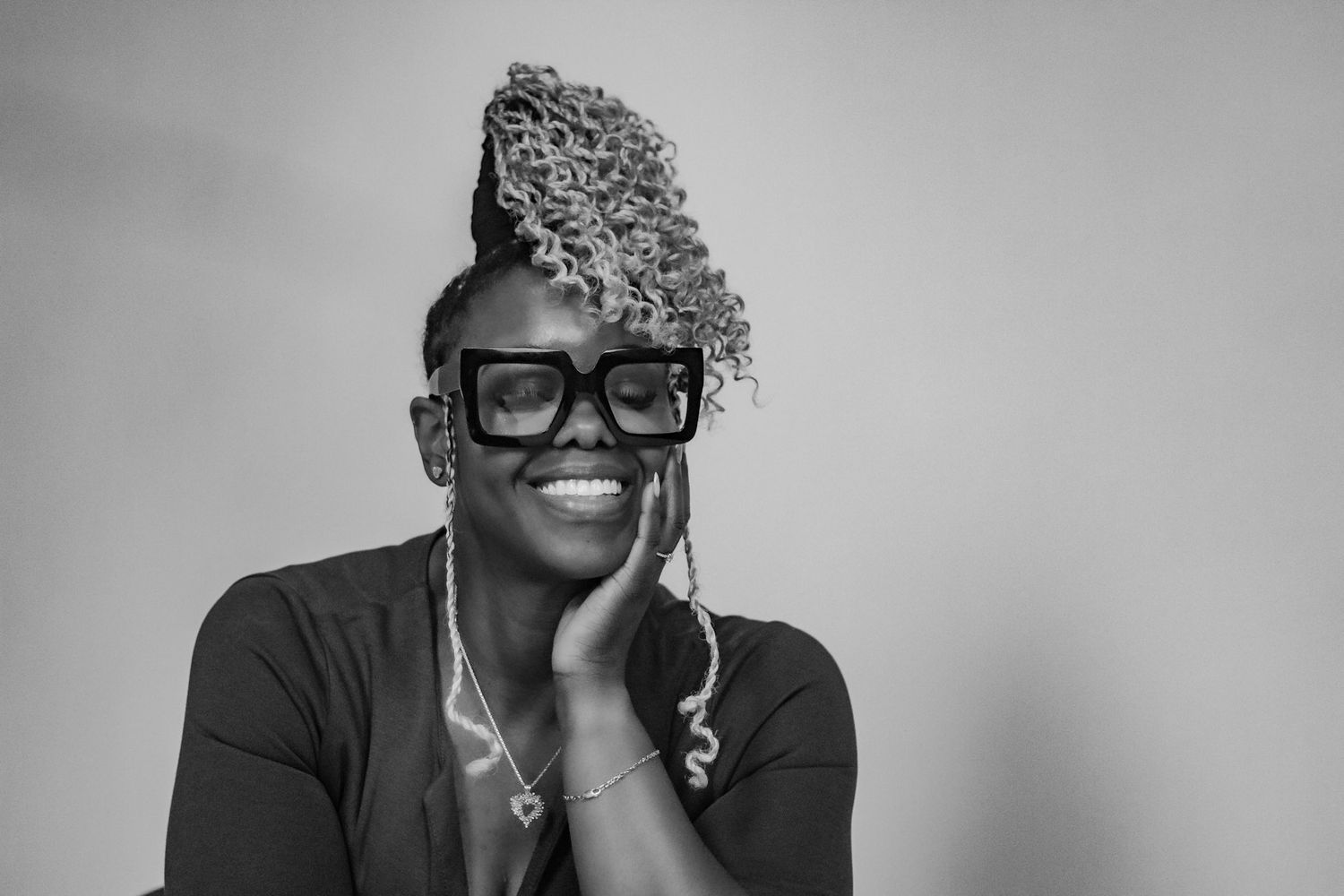 Black and white portrait of someone in glasses with curly hair styled to one side.