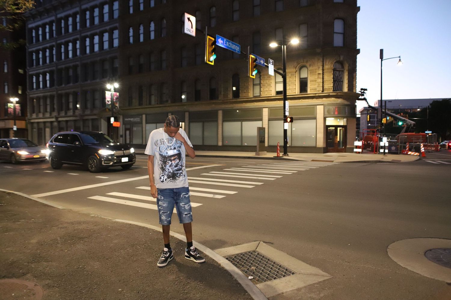 Empty urban intersection at night with street lights and building facades.