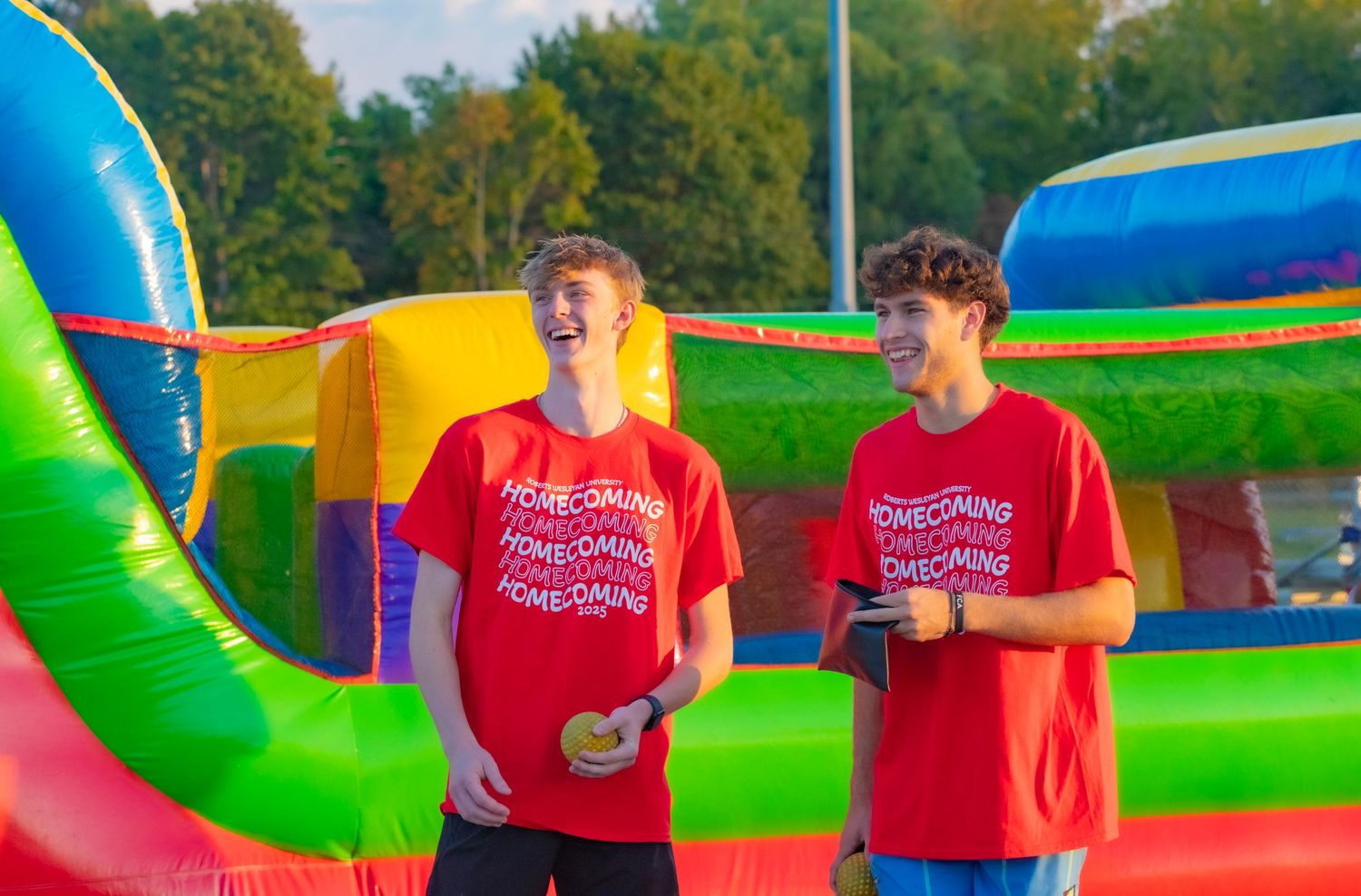 People in red t-shirts playing on colorful inflatable obstacle courses outdoors.