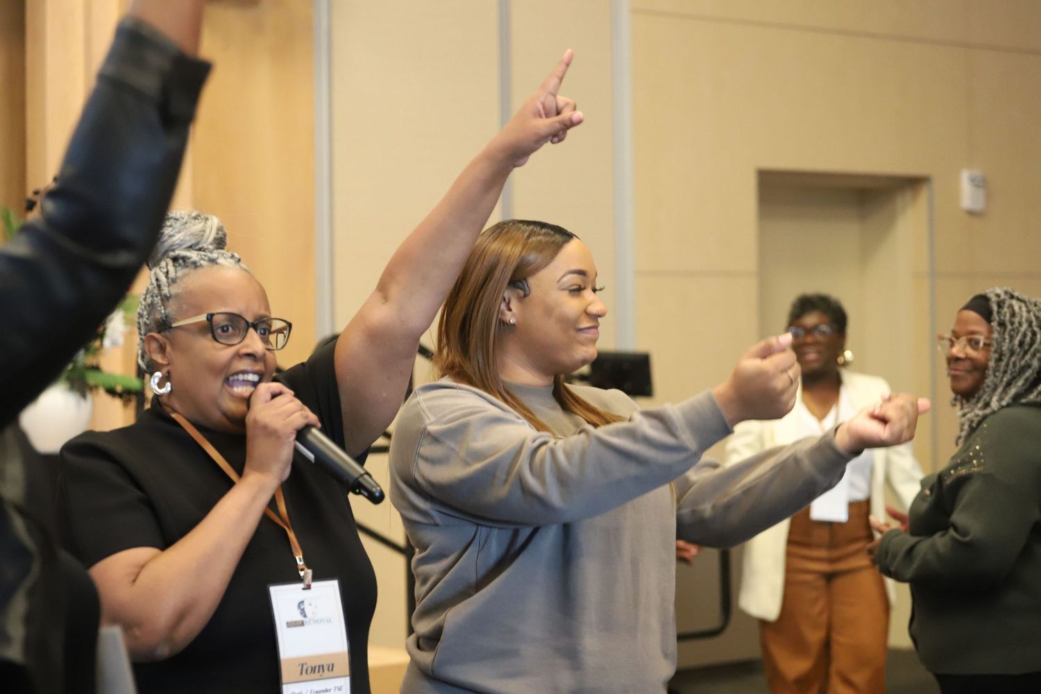 Indoor event with audience members raising hands during presentation.