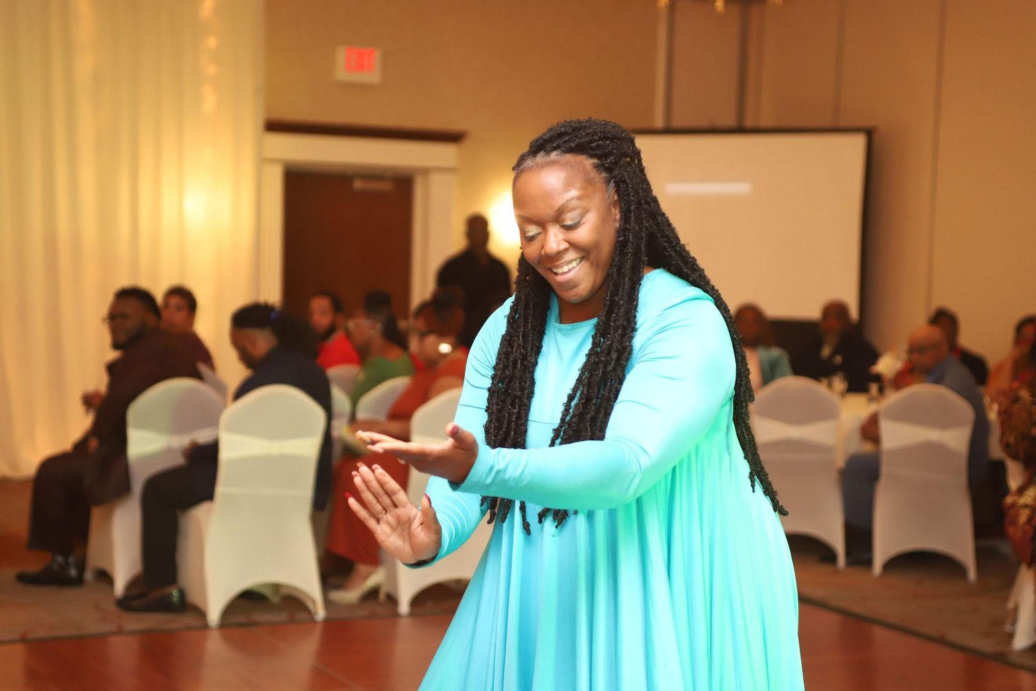 A performer in turquoise fabric creates dramatic movement during a dance routine.