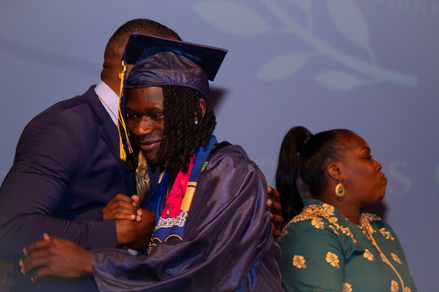 Graduation ceremony moment with people in formal attire and academic regalia.