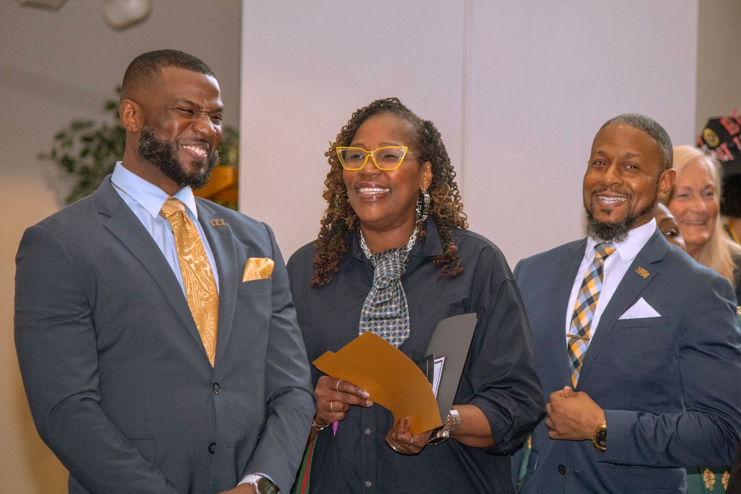 Group of professionally dressed people smiling during a formal event.