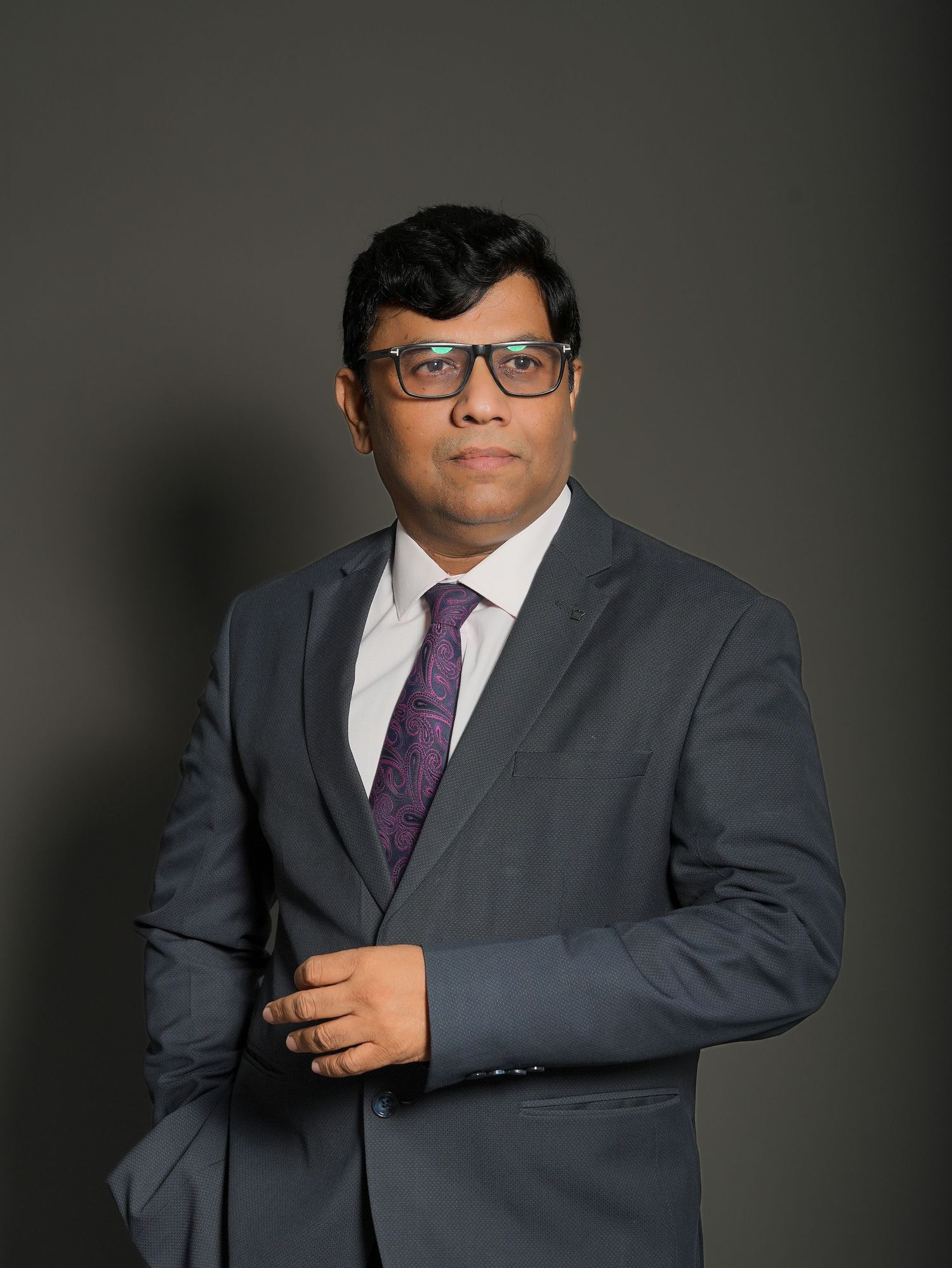 Professional portrait series in grey suit and purple tie against dark background.