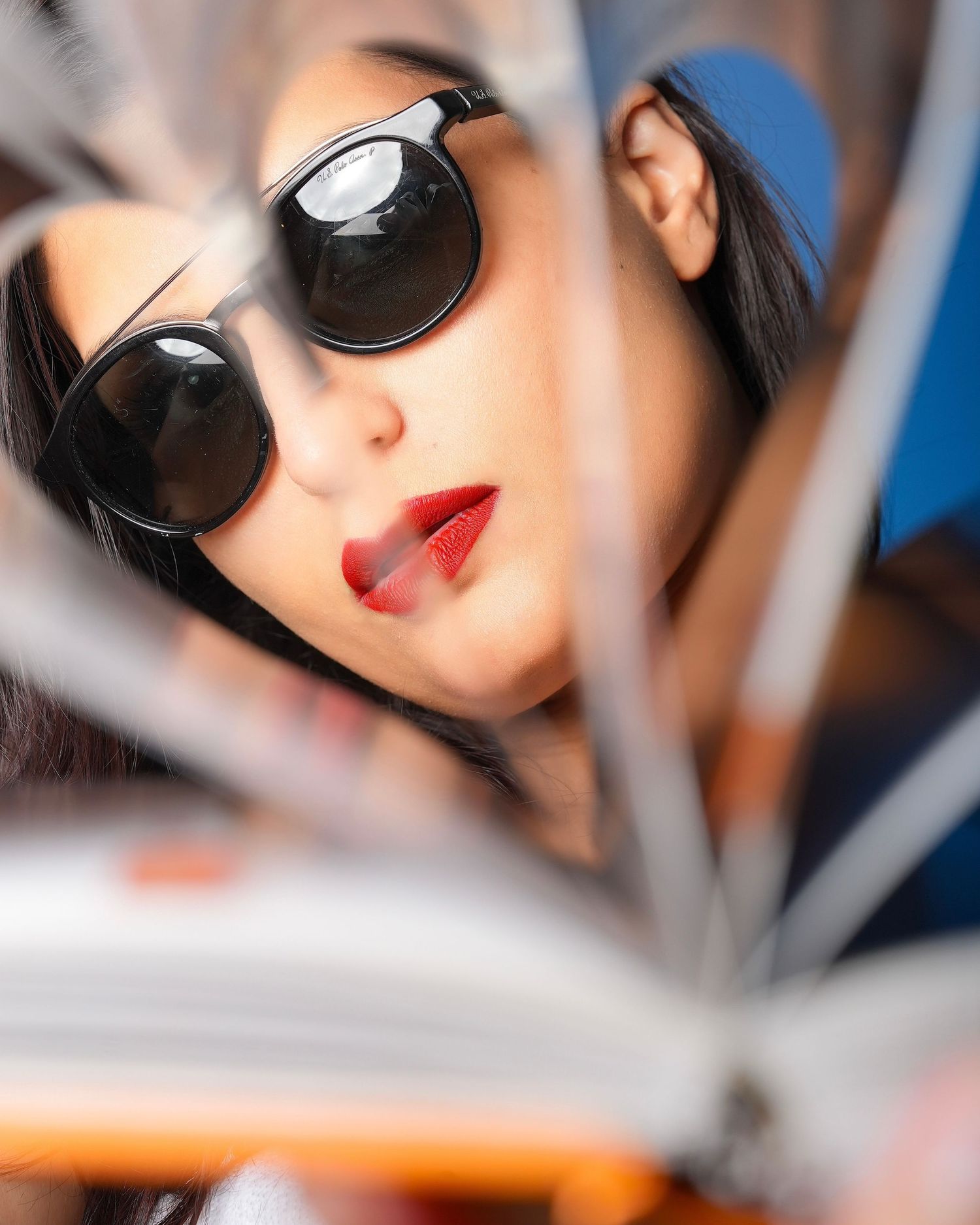 Artistic close-up shots of person wearing sunglasses with red lipstick in natural light.