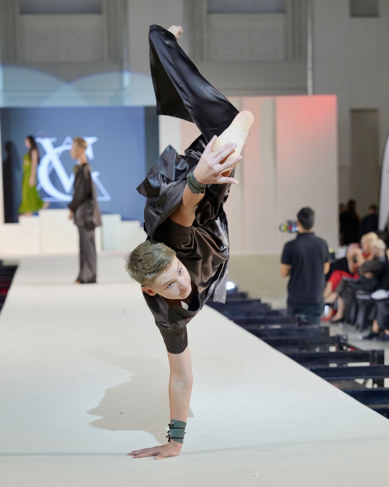 A performer executes a one-handed handstand on stage during a contemporary dance performance.