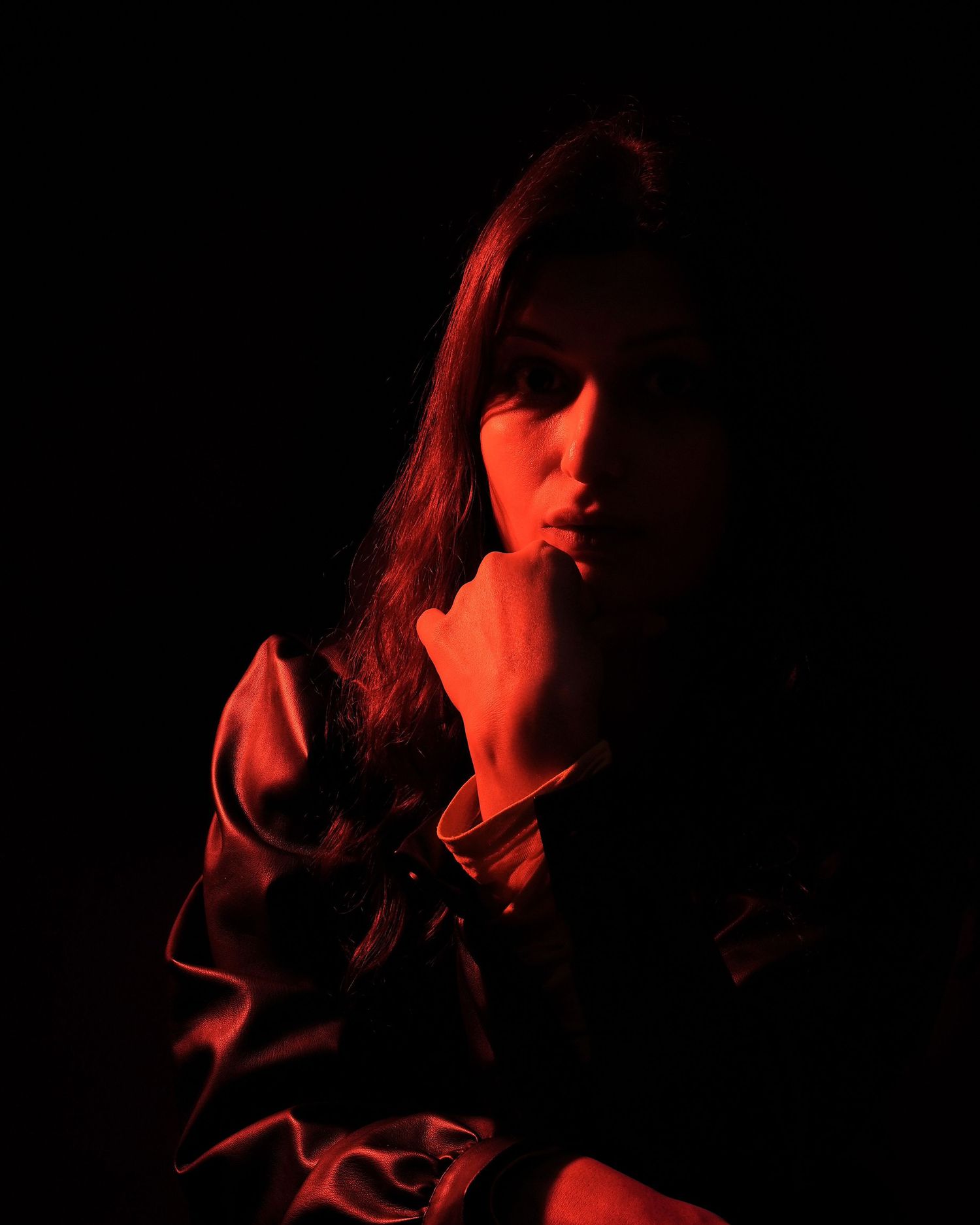 A series of dark atmospheric portraits illuminated by dramatic red lighting showing silhouetted figures in shadow.