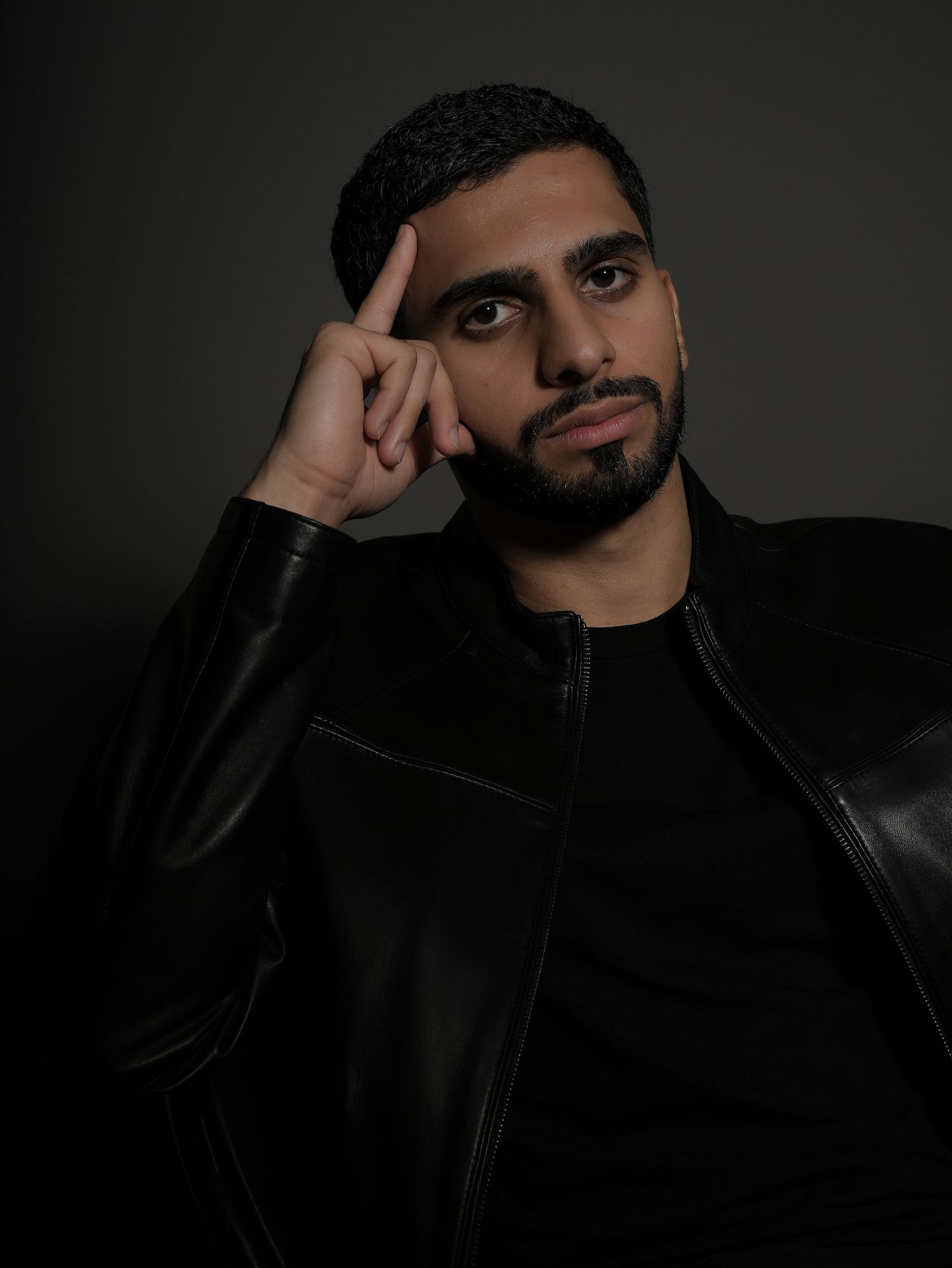A person wearing a black leather jacket poses against a dark background in a series of moody portrait shots.