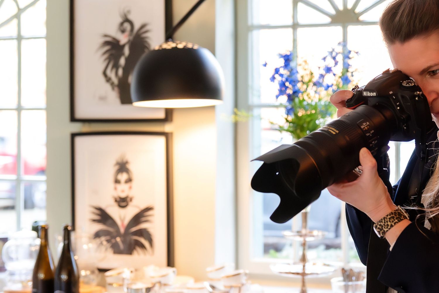 Photographer capturing shots with a professional DSLR camera in an elegant indoor setting with artwork on walls.