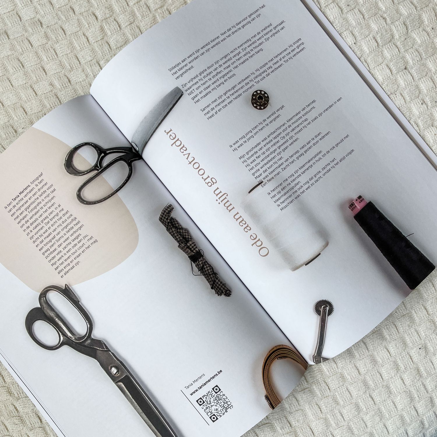 Open book with scissors, lipstick, hair clip, and small accessories arranged on white textured surface.
