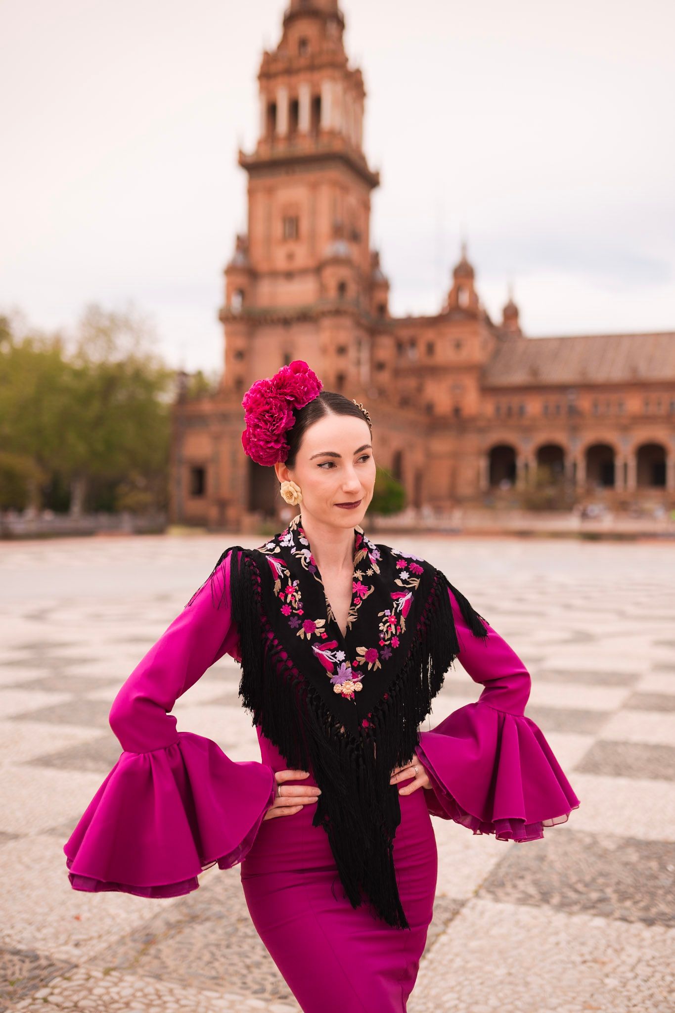 Flamenco dancer in magenta dress with black embroidered shawl at Plaza de España, Seville, Spain.
